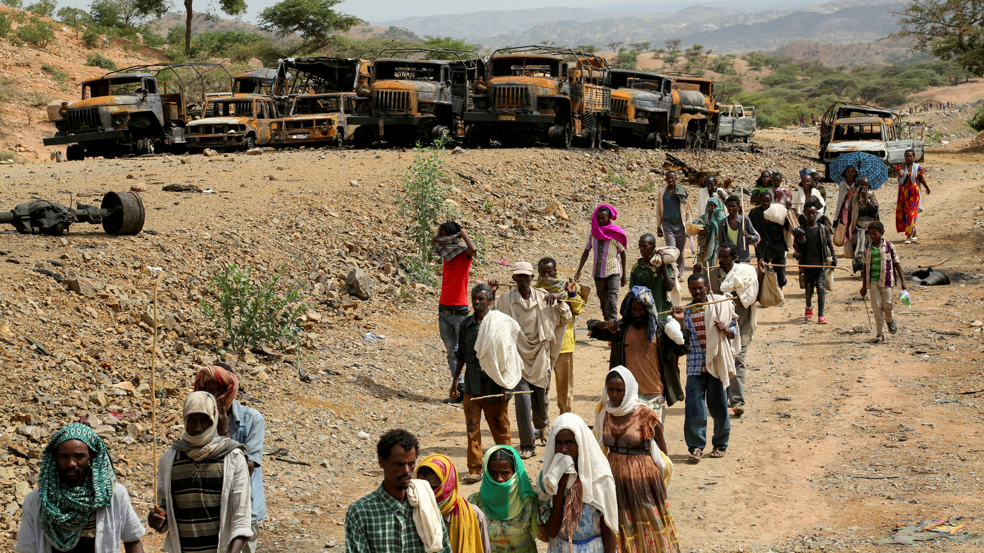 Dorfbewohner laufen in Tigray, Äthiopien an verbrannten Fahrzeugen vorbei. | REUTERS
