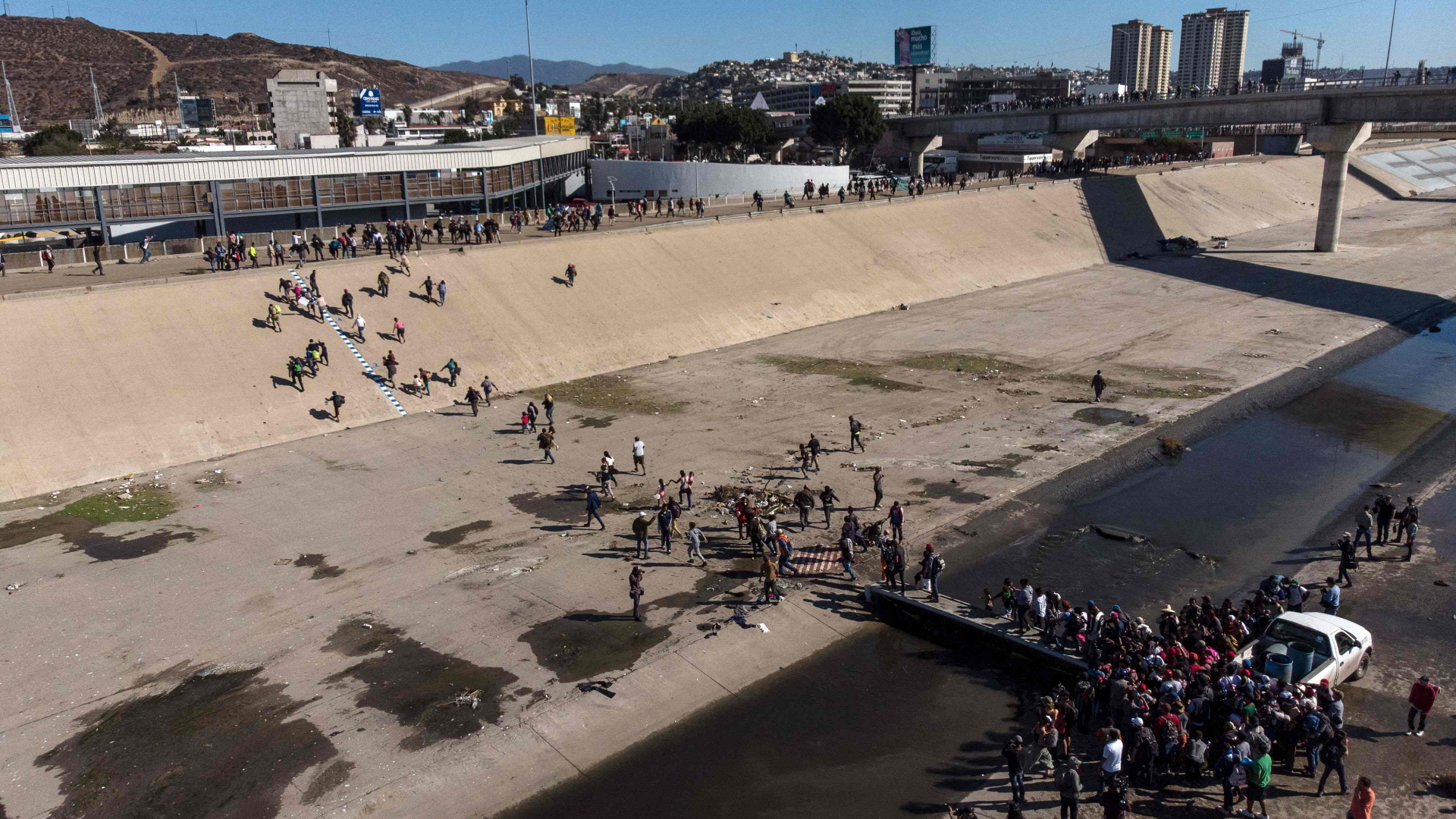 Eine Gruppe von Migranten überquert das ausgetrocknete Flussbett des Tijuana-Flusses. | Bildquelle: AFP