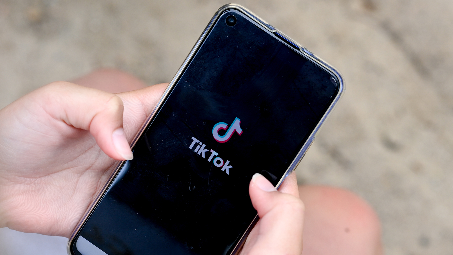 Ein Mädchen hält ein Smartphone in den Händen, auf dem das Logo der Kurzvideo-App TikTok zu sehen ist. | picture alliance/dpa/dpa-Zentral