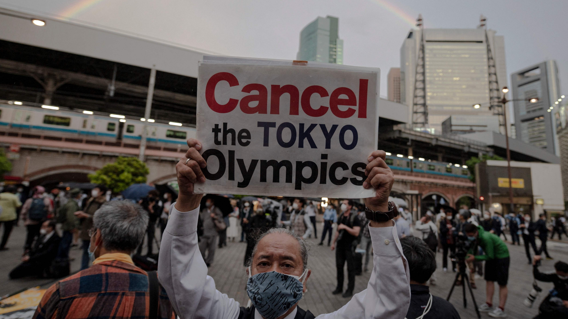 In Tikop hält ein Mann ein Schild in die Höhe, auf dem er die Absage der Olympischen Spiele fordert. | AFP
