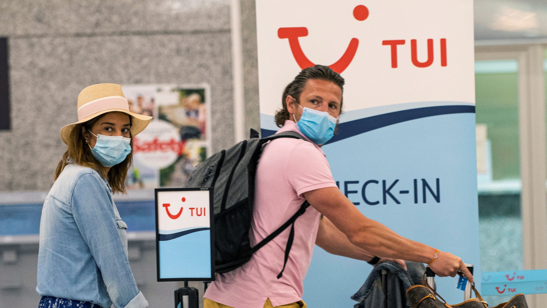 Zwei Urlauber mit Nasen-Mund-Schutz laufen zu einem Check-In-Schalter des Reiseanbieters TUI. | CATI CLADERA/EPA-EFE/Shutterstoc
