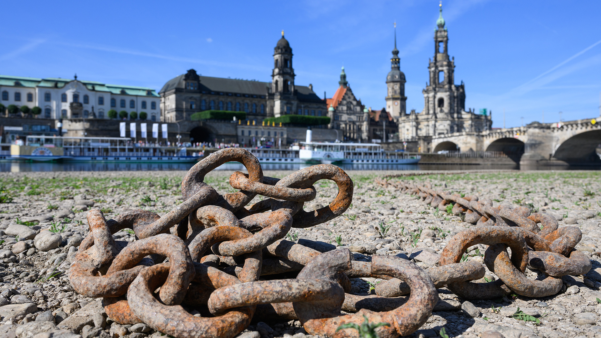 Ein verrostete Kette liegt am ausgetrockneten Elbufer vor der Altstadt von Dresden.