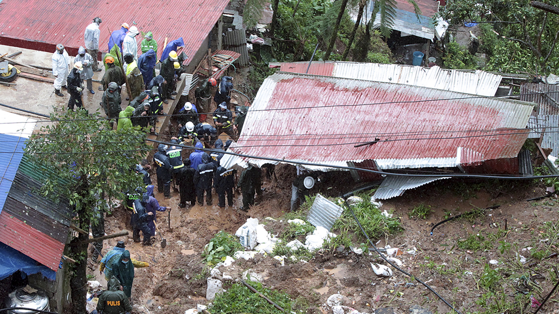 Menschen suchen nach Tropensturm nach Vermissten aus einem verschütteten Haus. | dpa