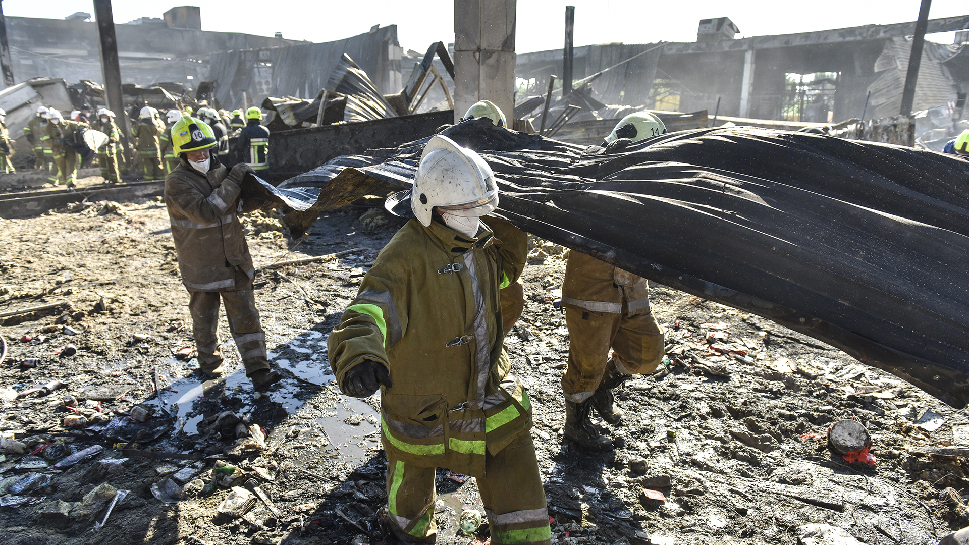 Feuerwehrleute entfernen die Trümmer eines zerstörten Einkaufszentrums in Krementschuk (Ukraine). | EPA