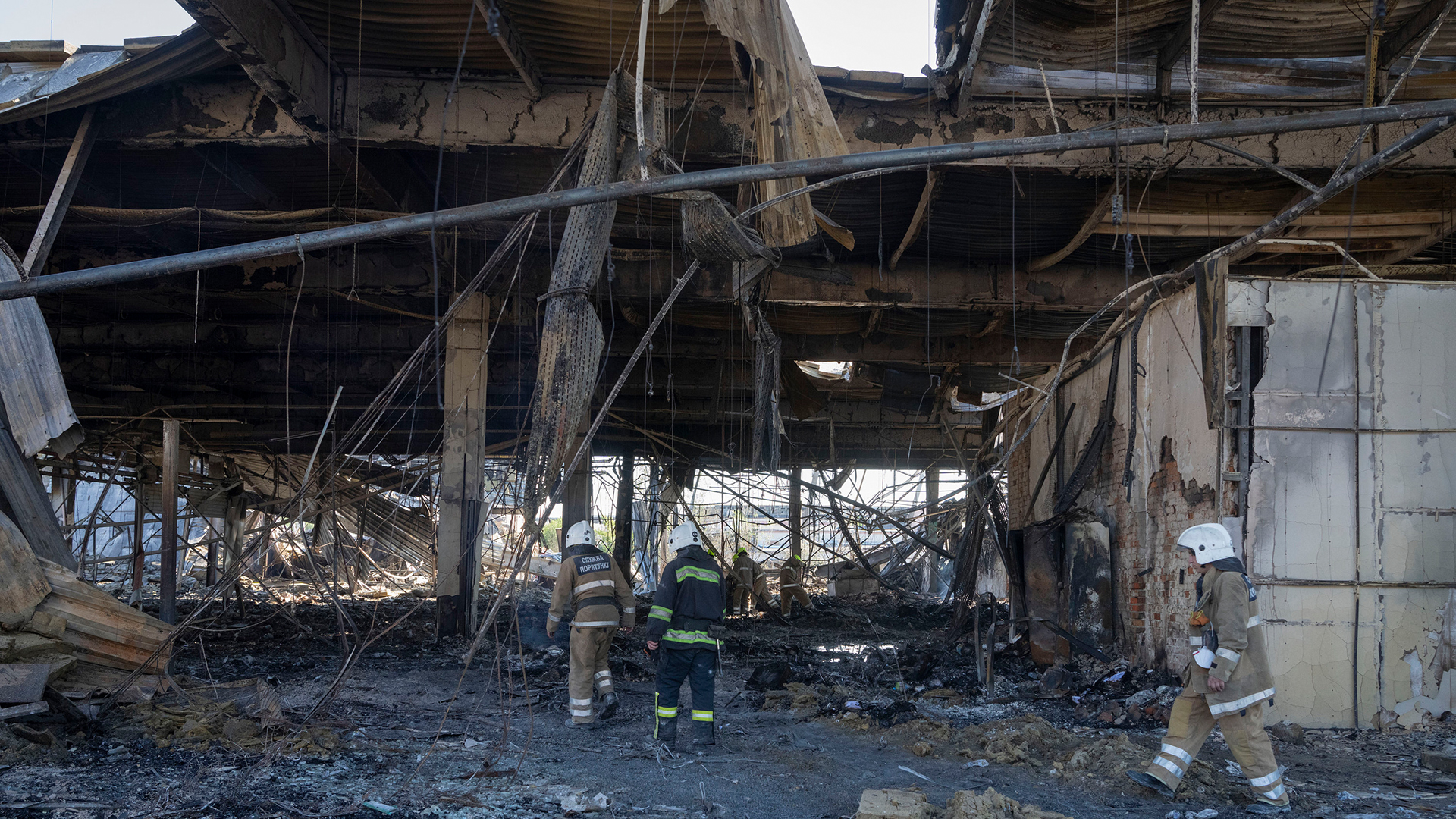 Feuerwehrleute entfernen die Trümmer eines zerstörten Einkaufszentrums in Krementschuk (Ukraine). | AP