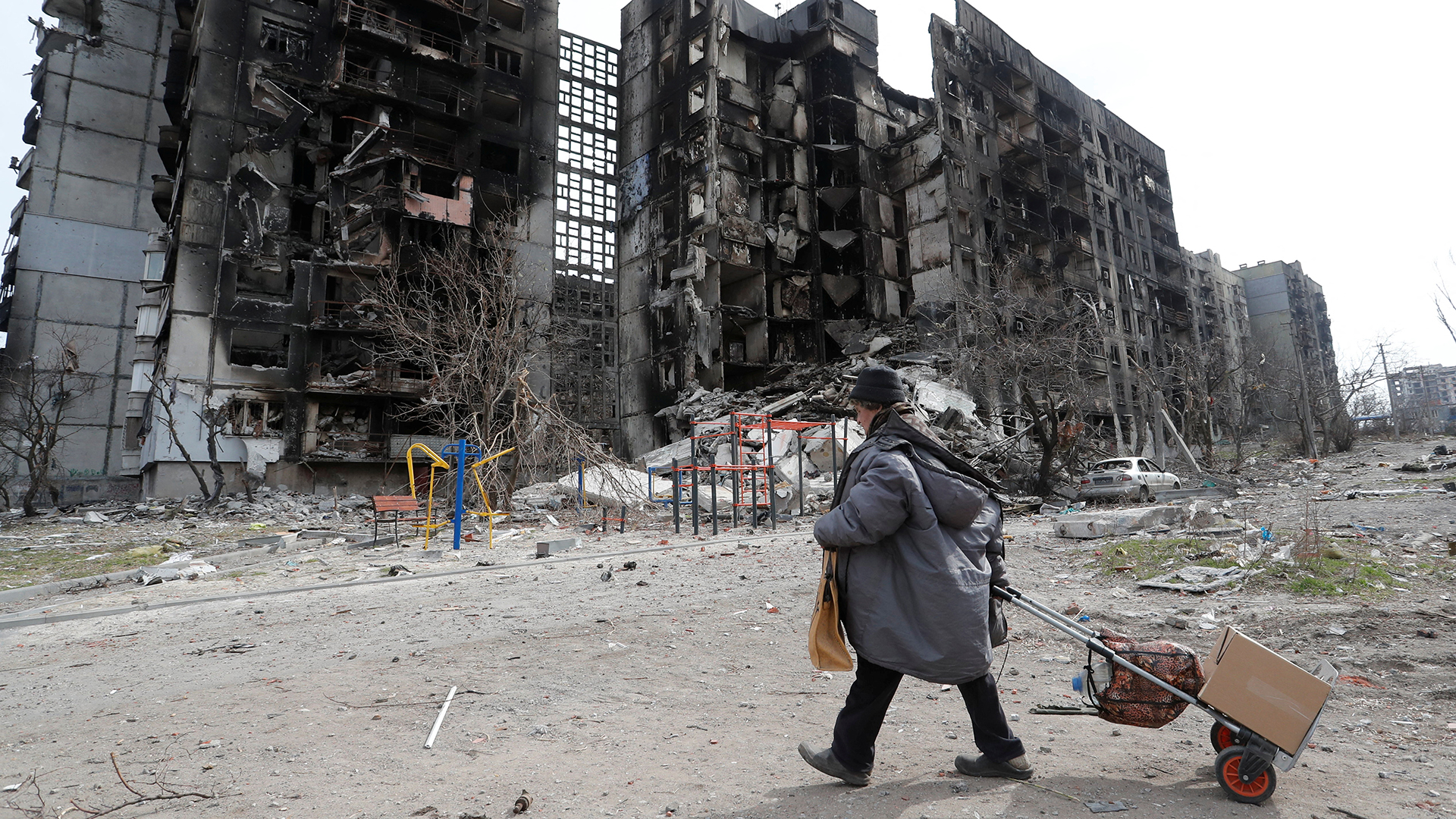 Ein Frau geht in Mariupol an einem zerstörten Haus vorbei. | REUTERS