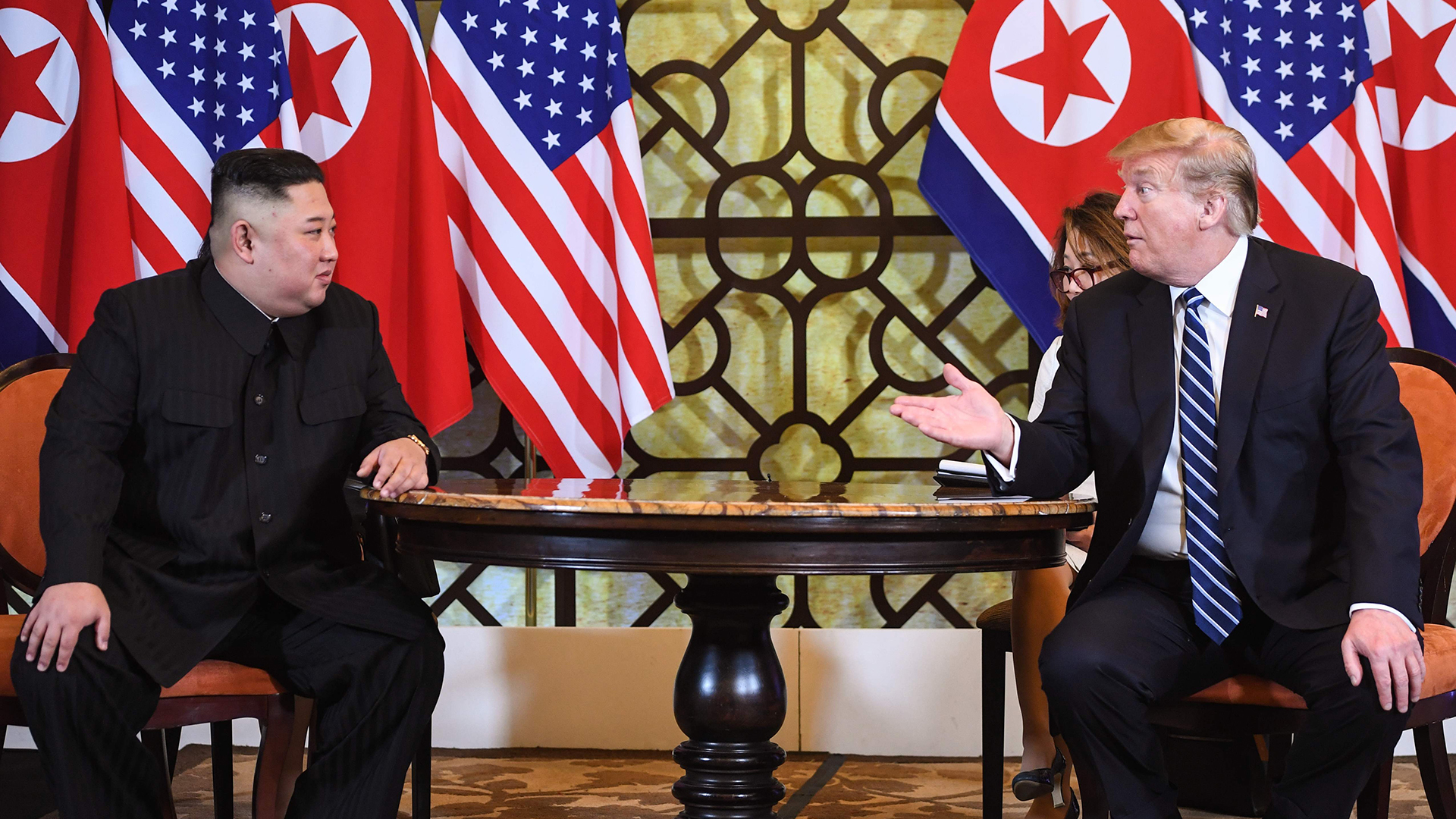 Kim Jong Un, Machthaber von Nordkorea, und Donald Trump, Präsident der USA, sitzen am Tisch vor Ihren Flaggen. | AFP