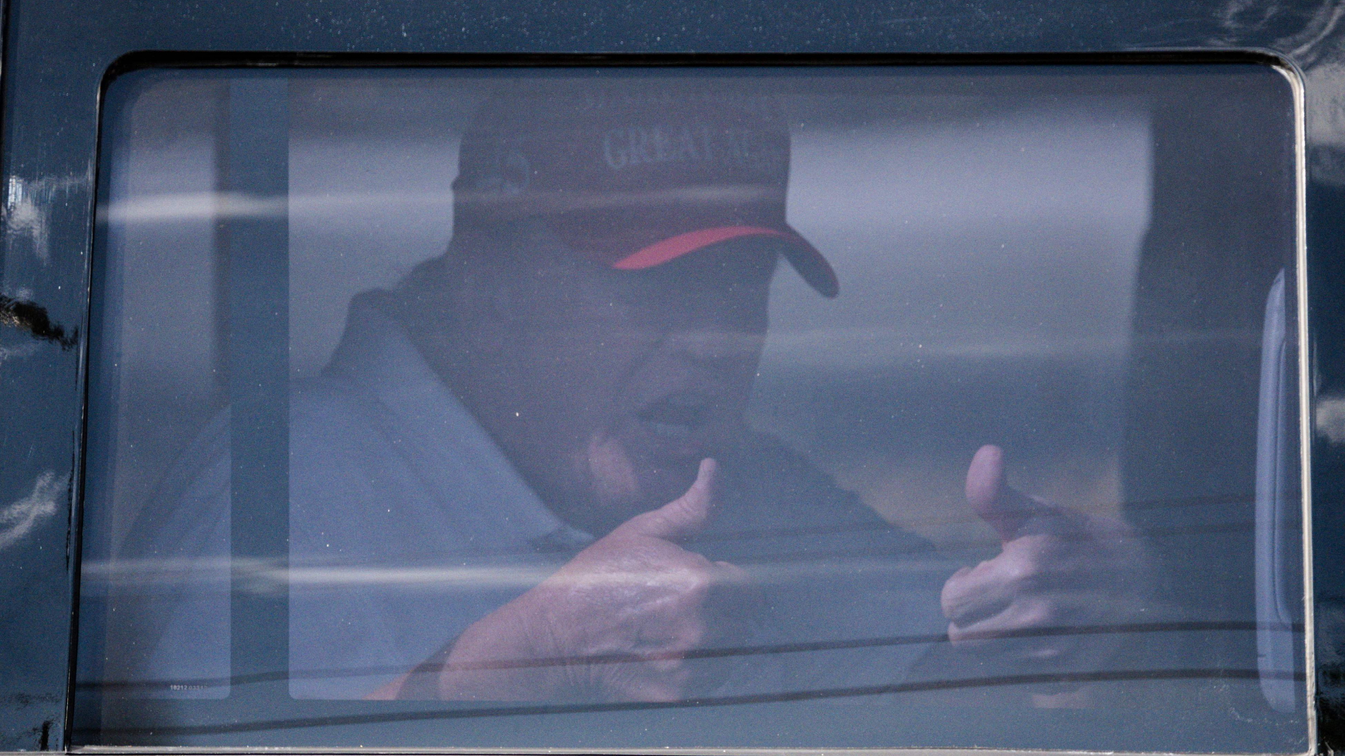 Der ehemalige US-Präsident Donald Trump sitzt in seiner Limousine und streckt zwei Daumen in die Luft.