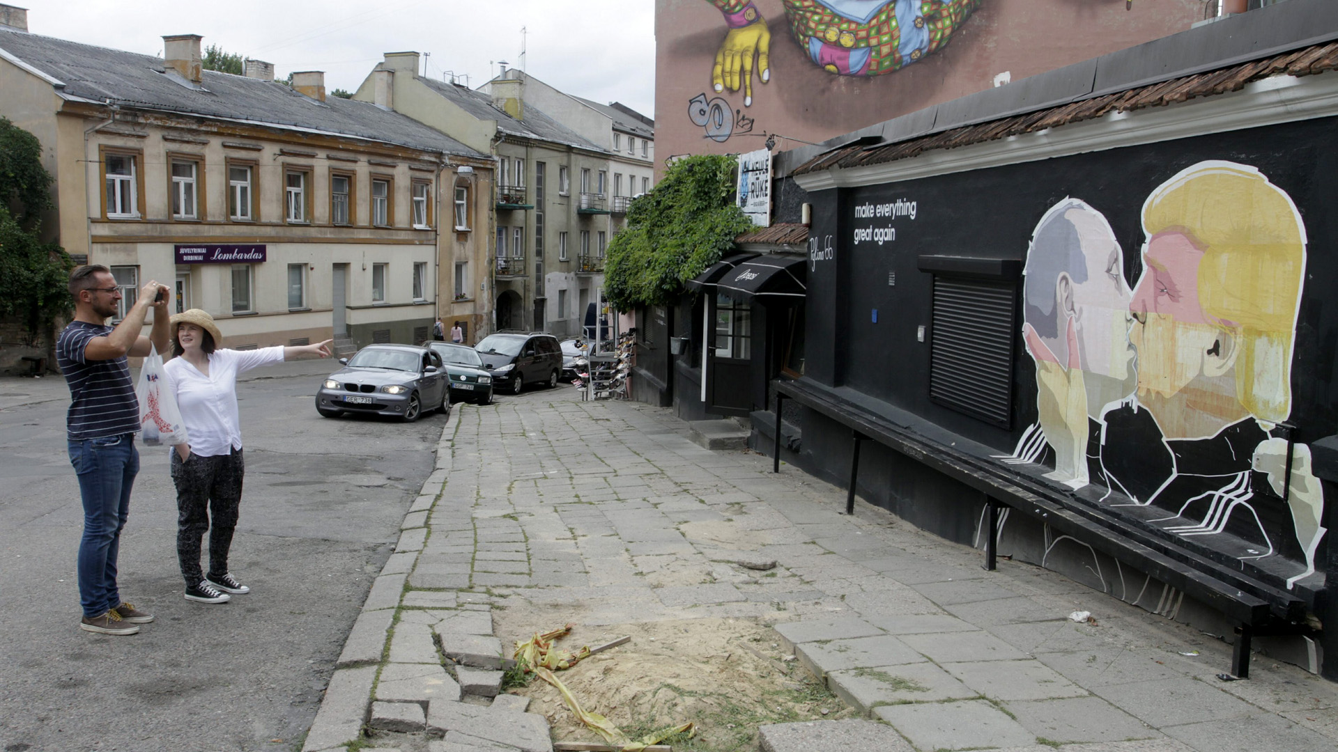 Menschen schauen sich ein Graffiti von Putin und Trump in Vilnius, Litauen, an. | dpa
