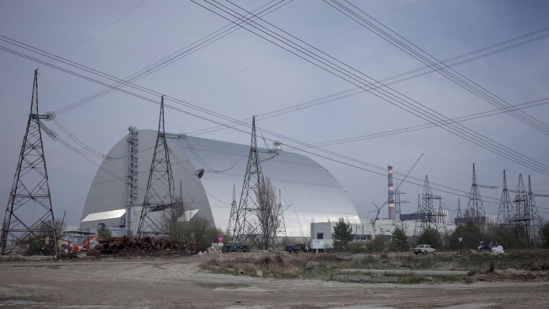 Stromleitungen über der neuen Schutzhülle des havarierten Atomreaktors im ukrainischen Tschernobyl. | REUTERS