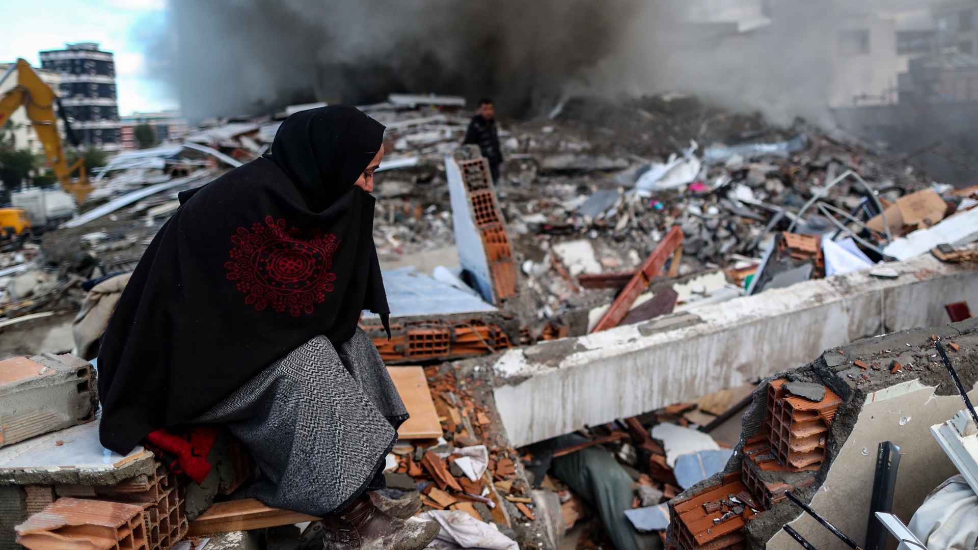 Eine verhüllte Frau sitzt auf den Trümmern eines eingestürzten Gebäudes. | EPA