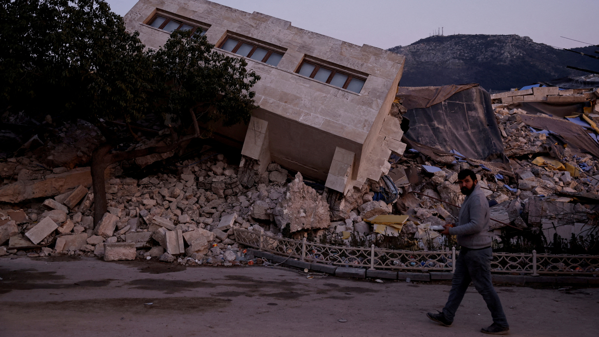 Ein Mann geht in der türkischen Stadt Antakya an vom verheerenden Erdbeben zerstörten Gebäuden vorbei. | REUTERS