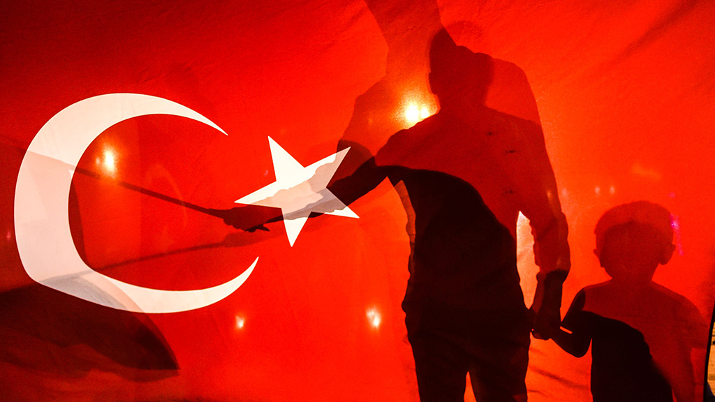 Die Schatten von Menschen sind durch eine türkische Fahne zu erkennen.