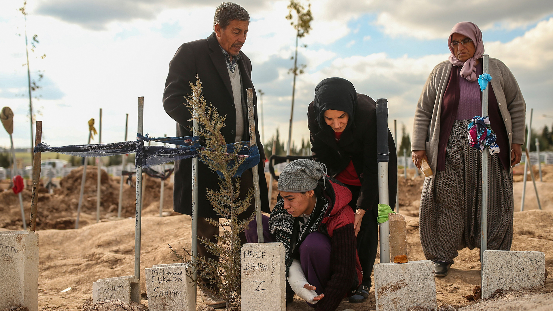 Vier Menschen trauern an einem Grab im türkischen Adiyaman