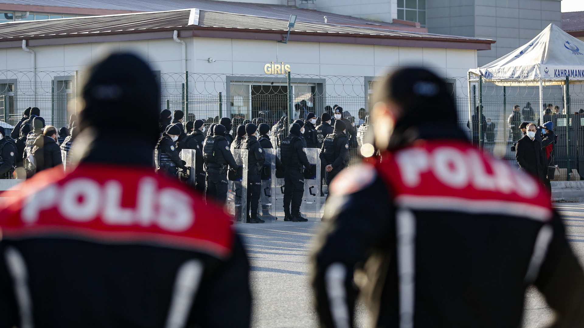 Zwei Polizisten stehen vor dem Gefängnis Sincan nahe Ankara, im Hintergrund stehen Insassen Schlange, die sich noch am selben Tag vor Gericht wegen des gescheiterten Putschs 2016 verantworten sollen. | AFP
