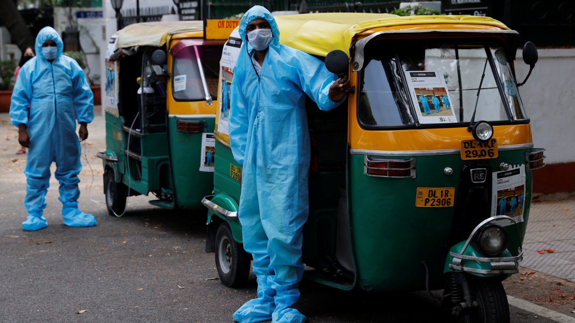 Zwei Männer in Schutzanzügen stehen vor ihren Tuktuks | REUTERS
