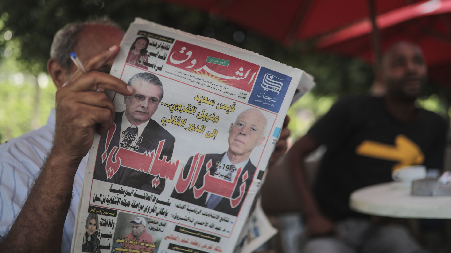 Ein Mann liest eine Zeitung, auf deren Titelseite die beiden führenden Kandidaten abgebildet sind. | AP