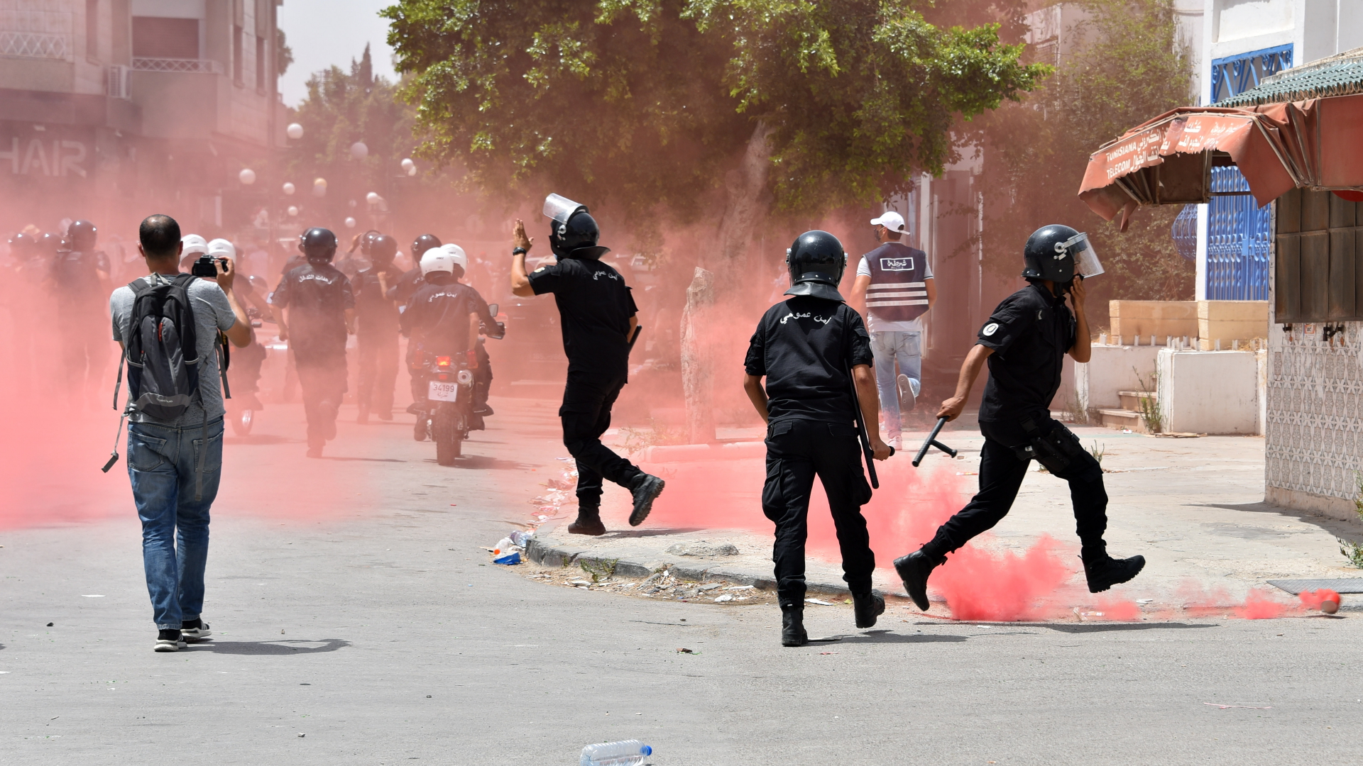  Tunesische Sicherheitskräfte werden bei einer Kundgebung gegen die Ennahdha-Partei und die Regierung von rotem Rauch eingehüllt. | dpa