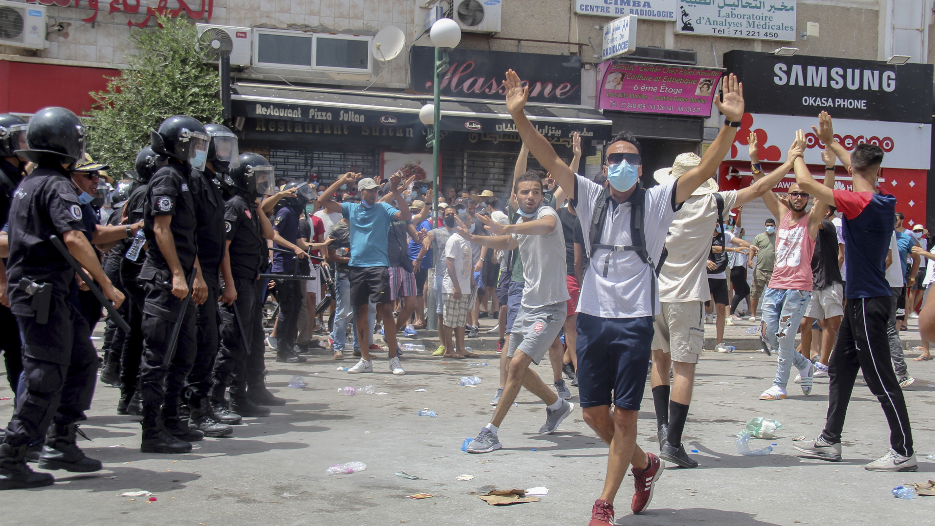 Uniformierte Polizisten stehen Demonstranten in Tunis gegenüber. | dpa