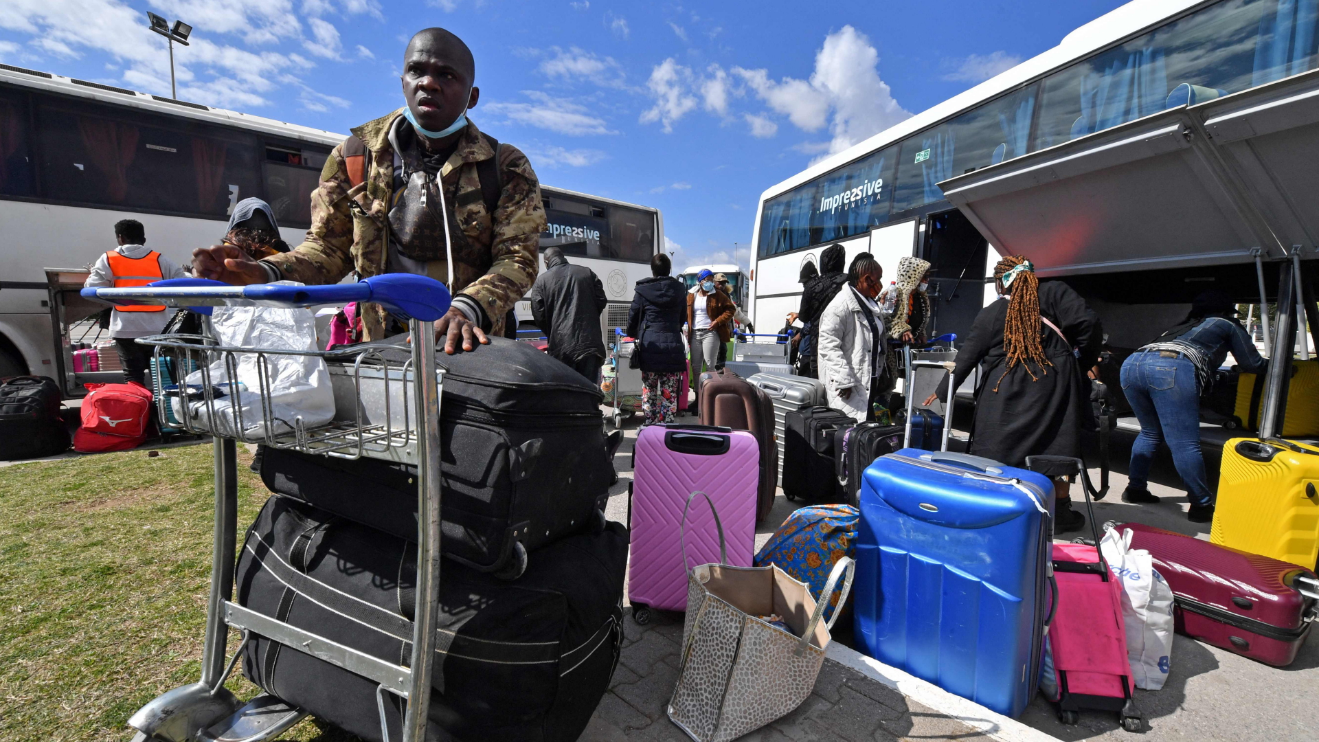 Migranten kommen mit ihrem Gepäck am Flughafen Tunis an, um in ihre Heimatländer auszureisen. | AFP