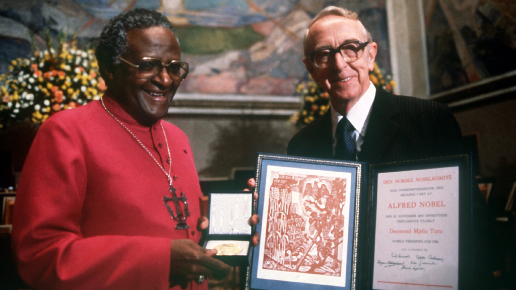 Egil Aarvik (rechts), der Vorsitzende des norwegischen Nobelpreiskomitees, überreicht am 10. Dezember 1984 in Oslo Desmond Tutu den Friedensnobelpreis. Der schwarze südafrikanische Anglikaner-Bischof wurde für seine Rolle als Führer und Einiger der Bewegung zur Lösung der Apartheid-Probleme in Südafrika ausgezeichnet worden. | picture-alliance/dpa