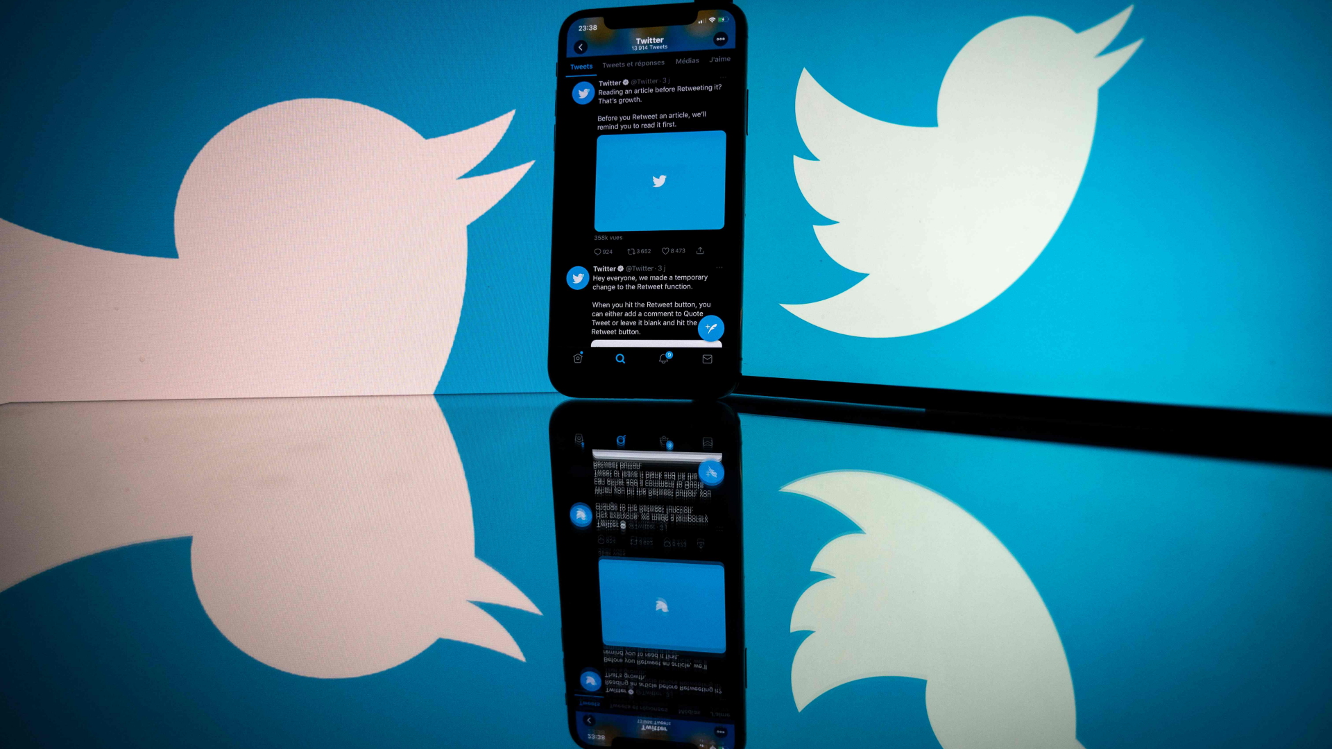 Übergroßes Twitter-Logo und ein Smartphone spiegeln sich auf einer glänzenden Oberfläche | AFP