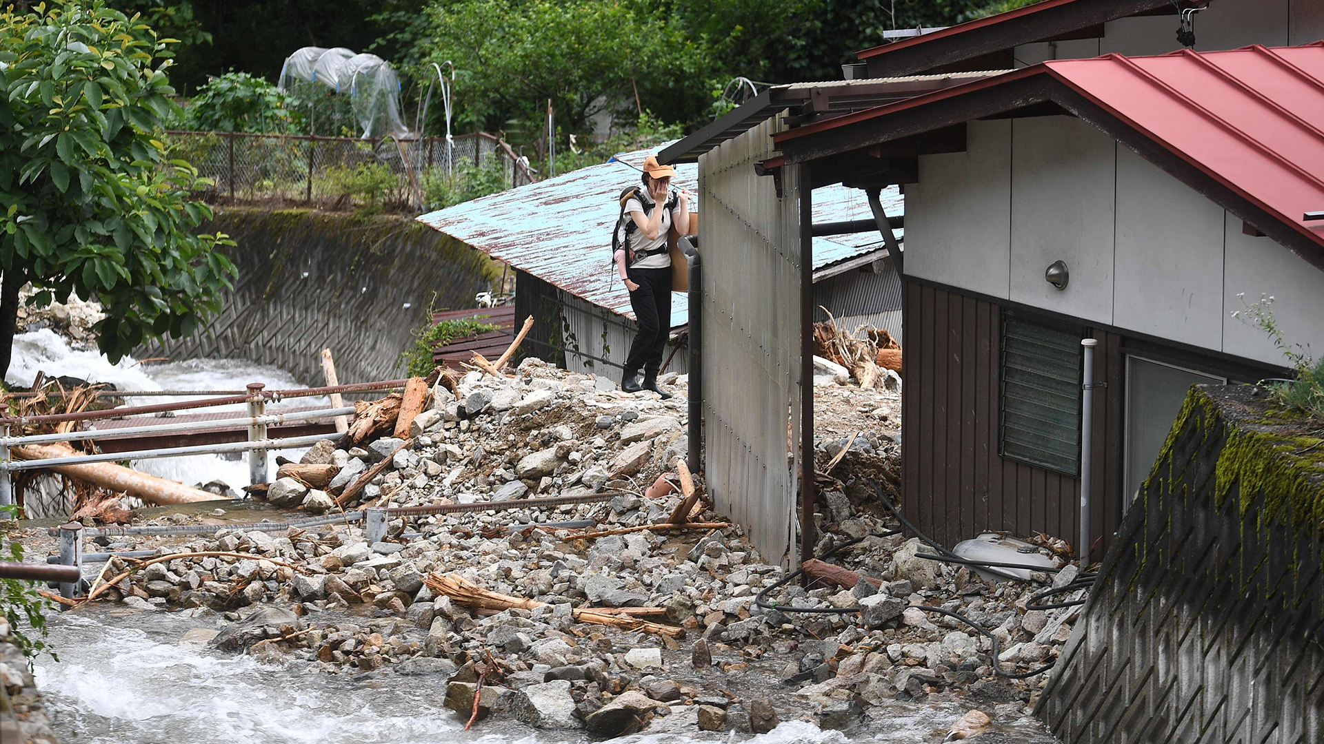 Eine Frau blickt auf ihr durch die Überschwemmungen zerstörtes Haus | AFP