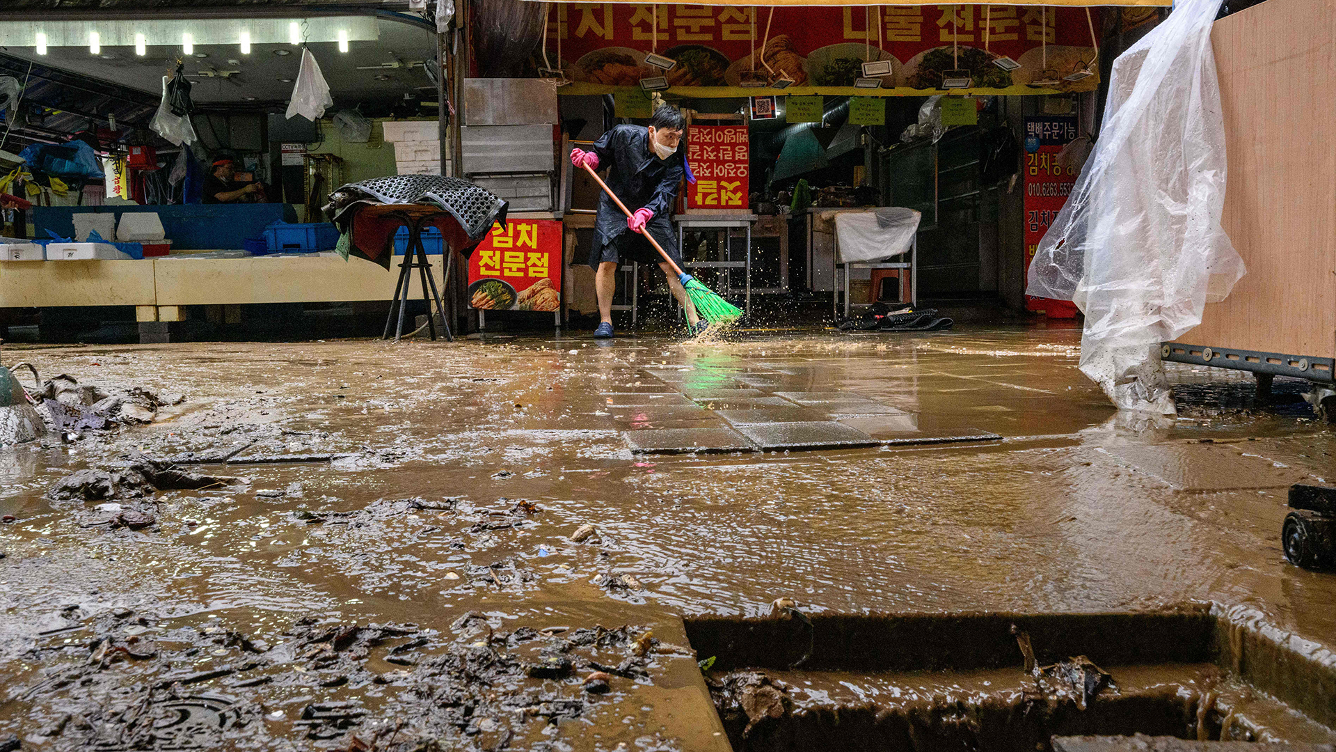Ein Arbeiter wischt auf dem historischen Namseong-Markt im Gangnam-Viertel von Seoul (Südkorea) Wasser und Schlamm der Überschwemmungen auf.  | AFP