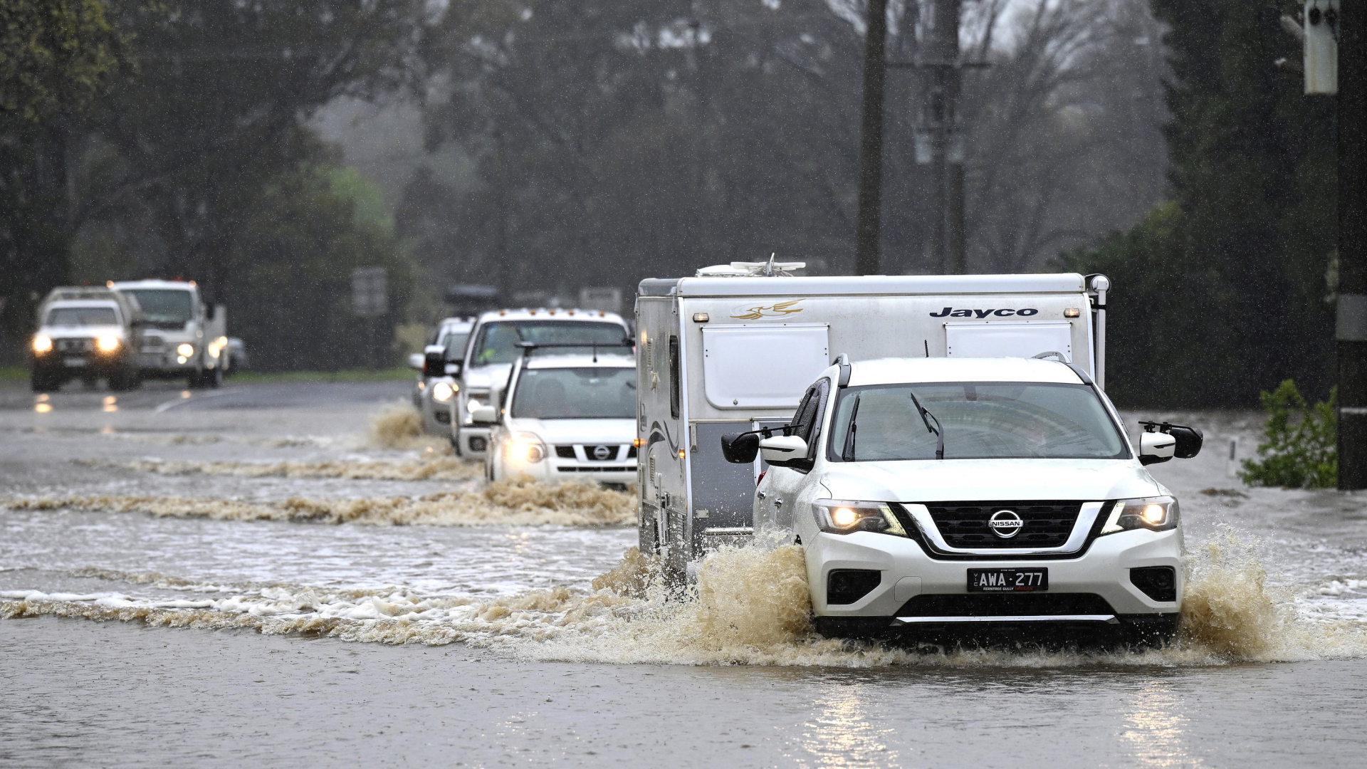 Autos fahren durch das Wasser auf einer überschwemmten Straße. | AP