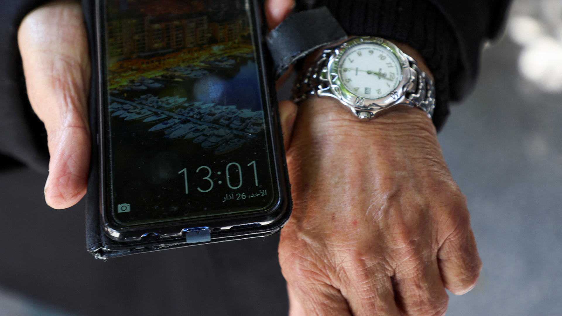 Ein Mann zeigt die unterschiedlichen Zeiten auf seiner Armbanduhr und seinem Telefon. | REUTERS