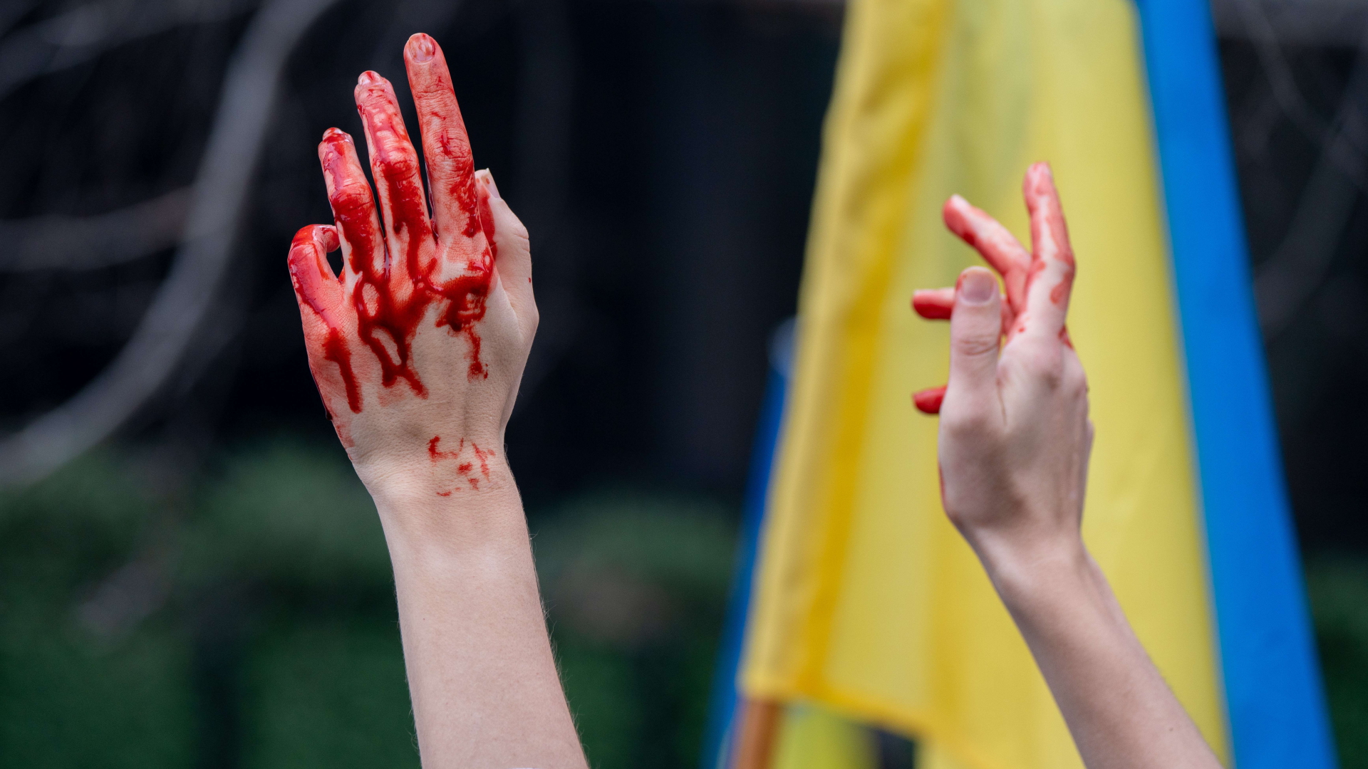 Kunstblut an den Händen einer Person, die an einer Solidaritätskundgebung für die Ukraine teilnimmt. | AFP