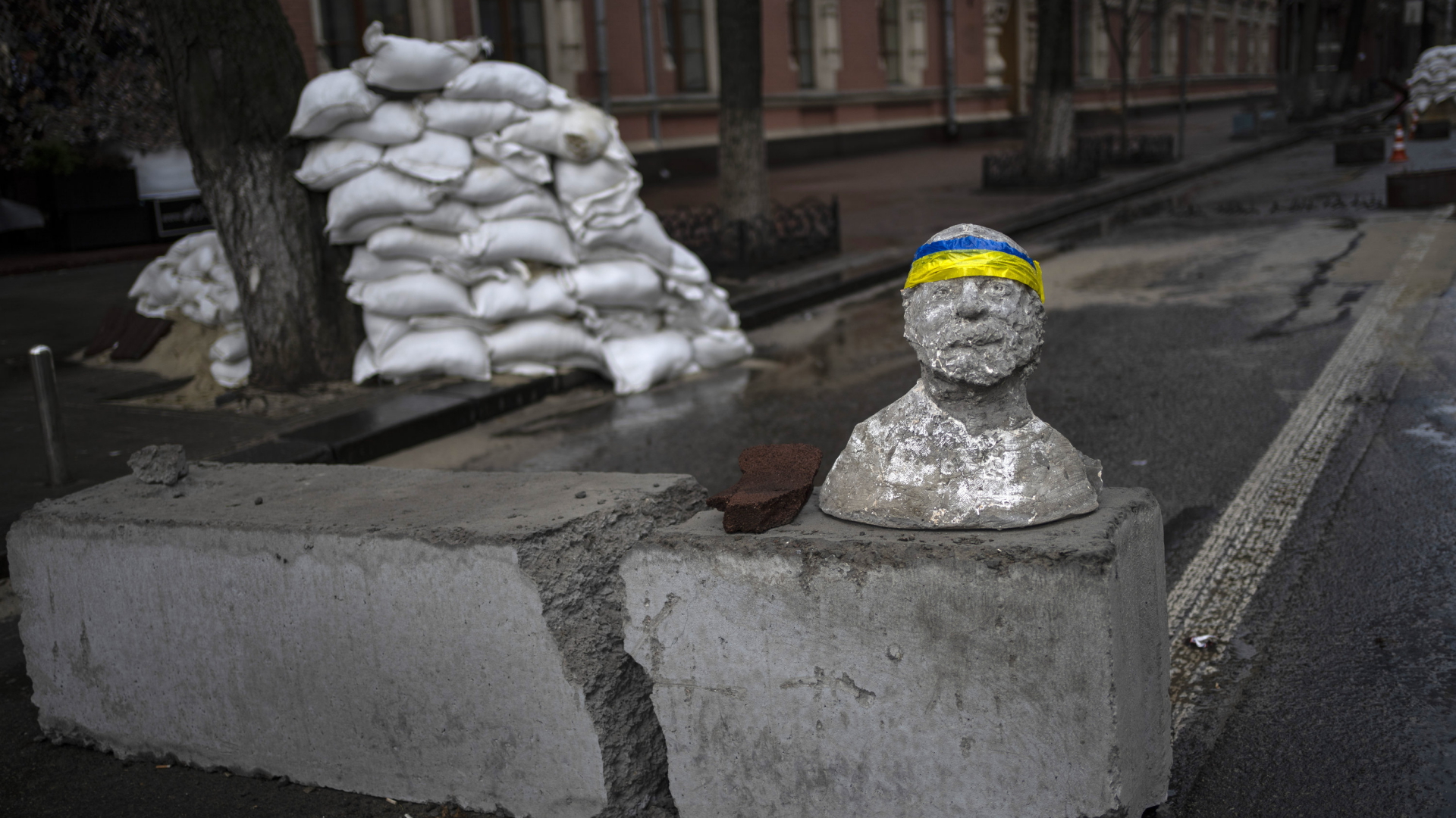 Ein auf eine Straßenbarrikade in Kiew gesetzter Statuenkopf trägt ein blau-gelbes Stirnband. | AP