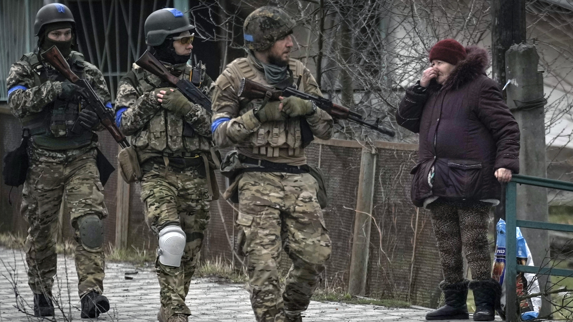 Eine Frau betrachtet ukrainische Soldaten, die in dem ehemals russisch besetzten Kiewer Vorort Bucha auf Patrouille sind. | dpa