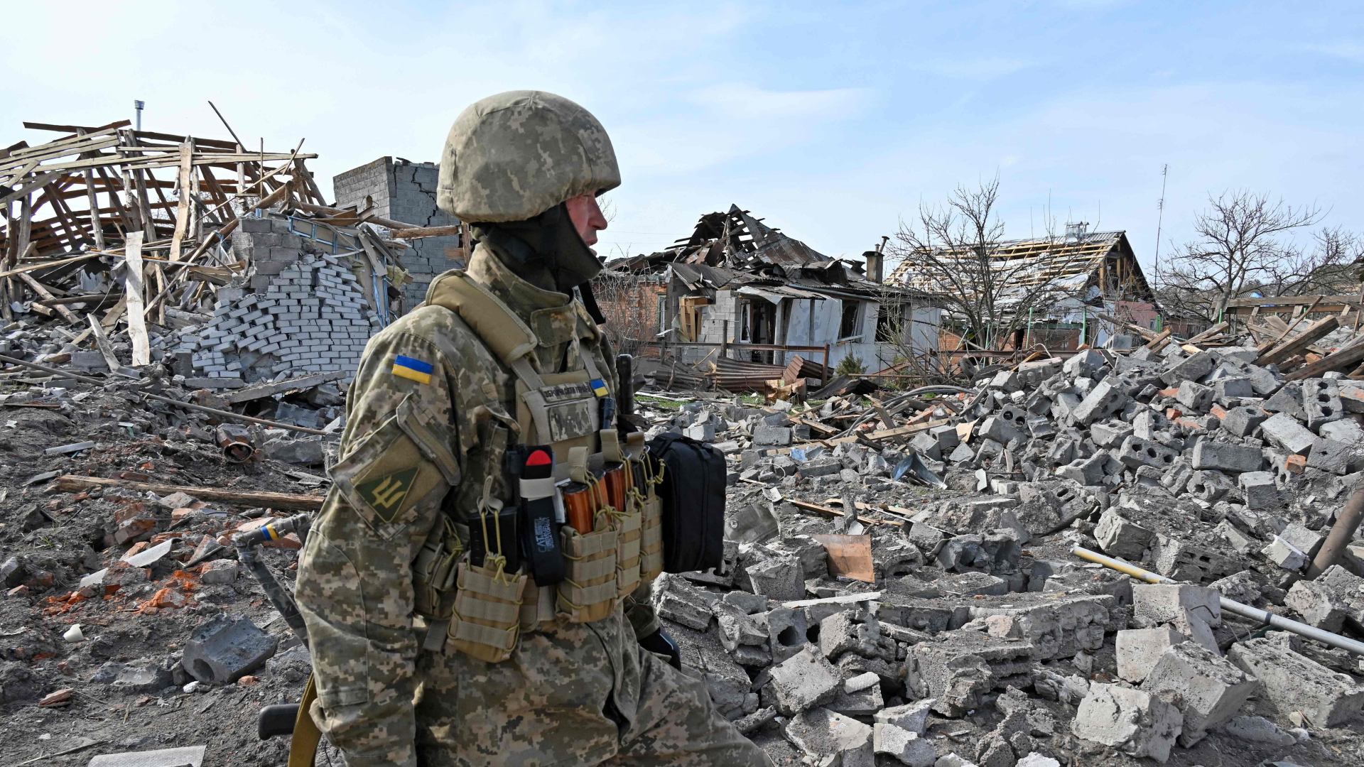 Ein ukrainischer Soldat vor einem zerstörten Haus bei Charkiw