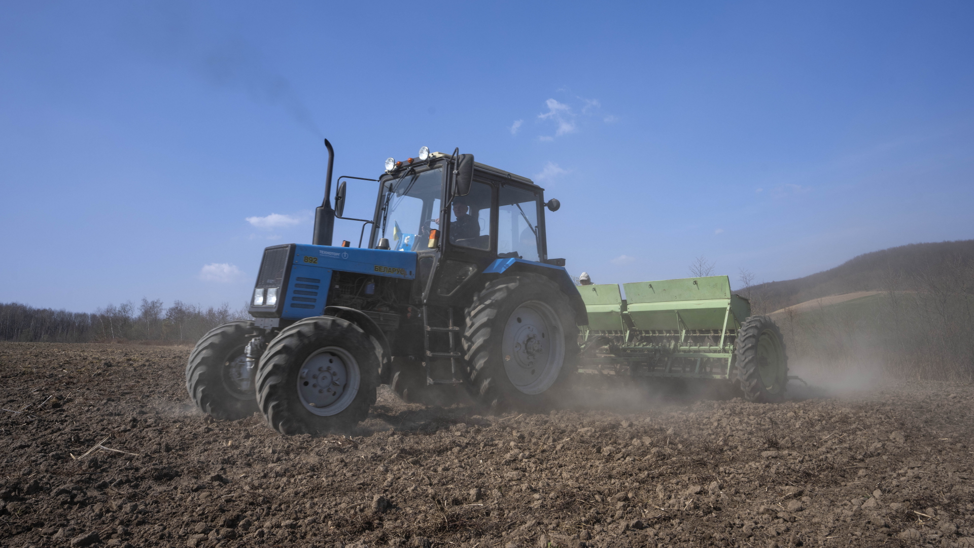 Arbeiter pflügen ein Weizenfeld im Westen der Ukraine (Archivbild). | dpa
