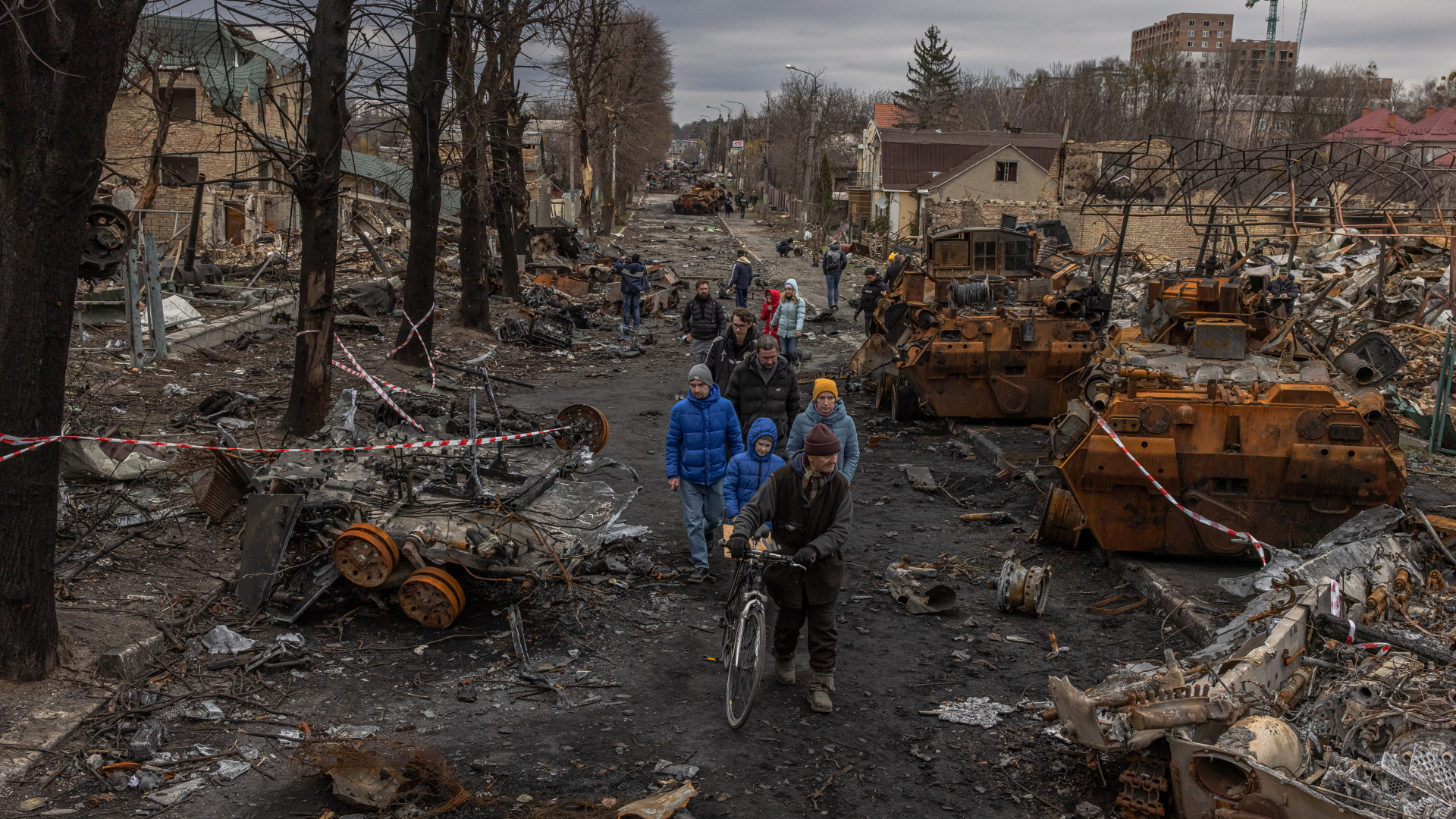 Bewohner gehen in Butscha an zerstörten russischen Militärmaschinen vorbei. | EPA
