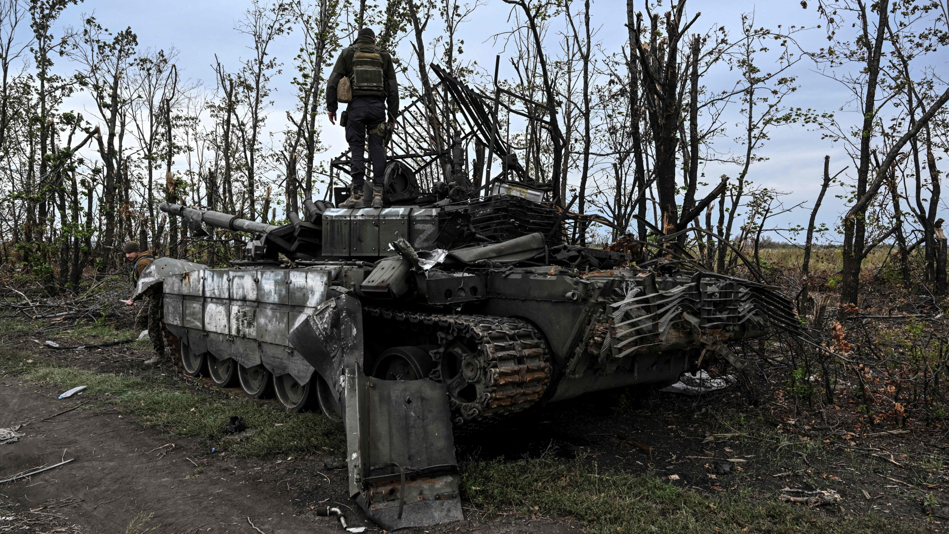 Ein ukrainischer Soldat steht auf einem schwer beschädigten russischen Kampfpanzer. Das Foto soll nahe Isjum entstanden sein. | AFP