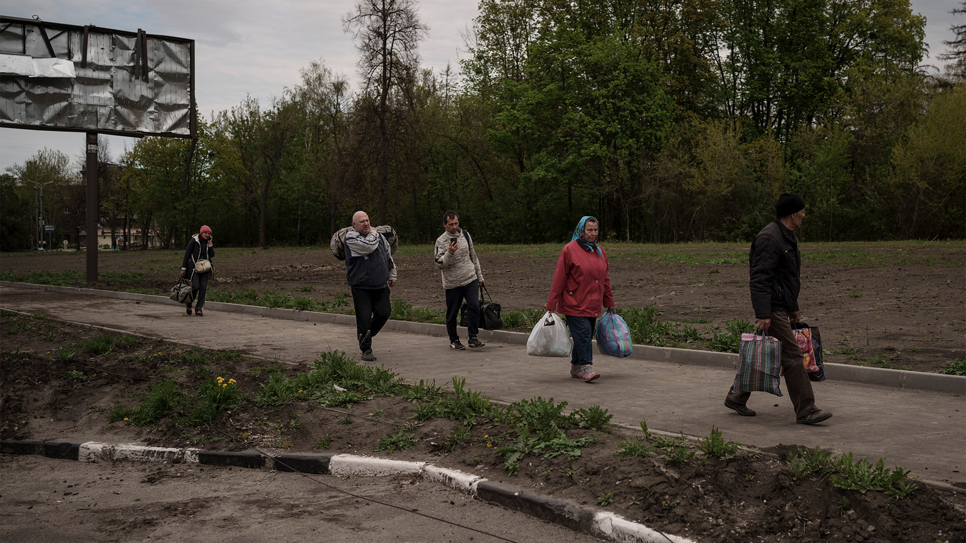 Menschen, die aus dem Dorf Ruska Losowa geflohen sind, gehen mit ihrem Gepäck zu einem Kontrollpunkt in Charkiw. | dpa