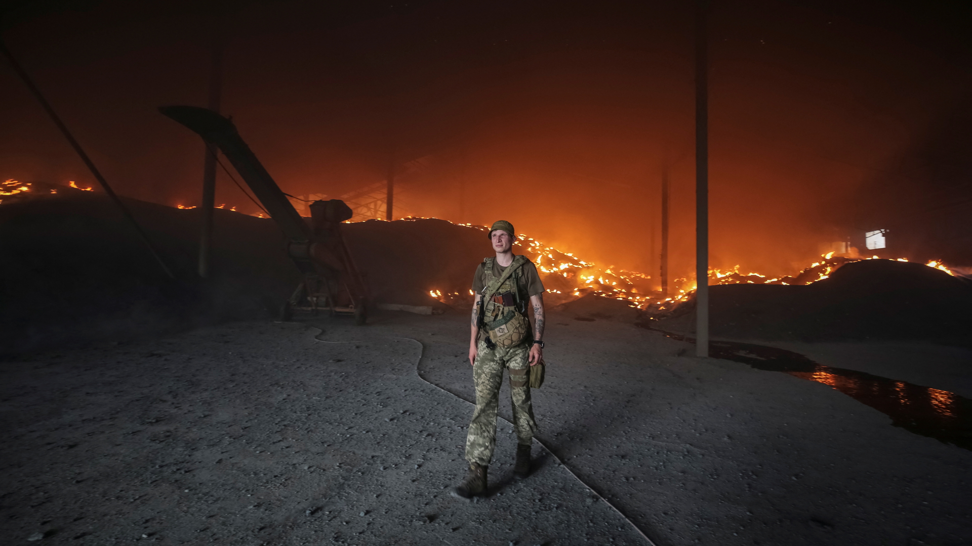 Ein ukrainischer Soldat vor einem brennenden Getreidesilo in der Donezker Oblast. | REUTERS