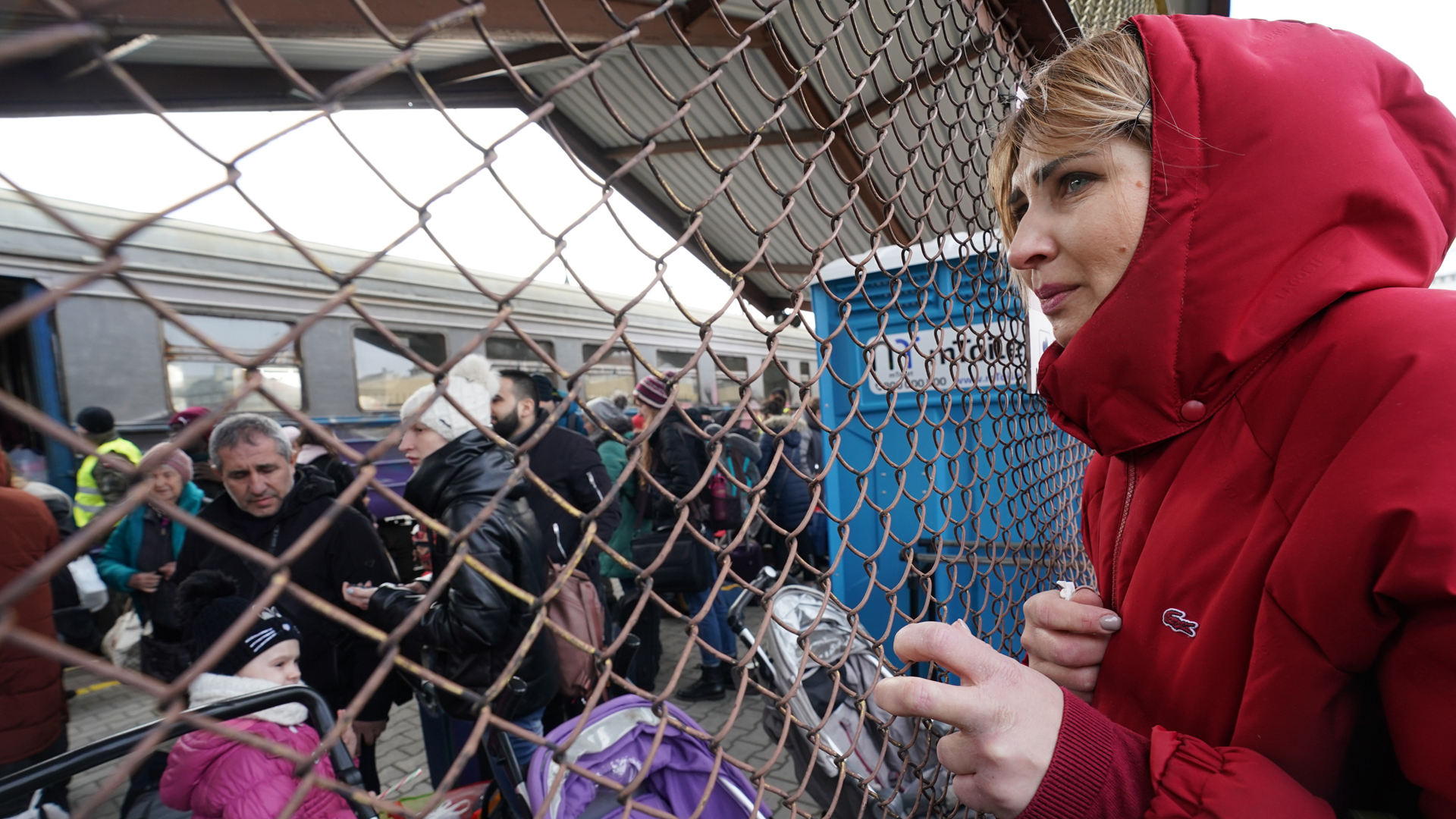 Eine Frau hält nach der Ankunft eines Zuges im polnischen Przemysl an einem Zaun Ausschau. | picture alliance / ZUMAPRESS.com