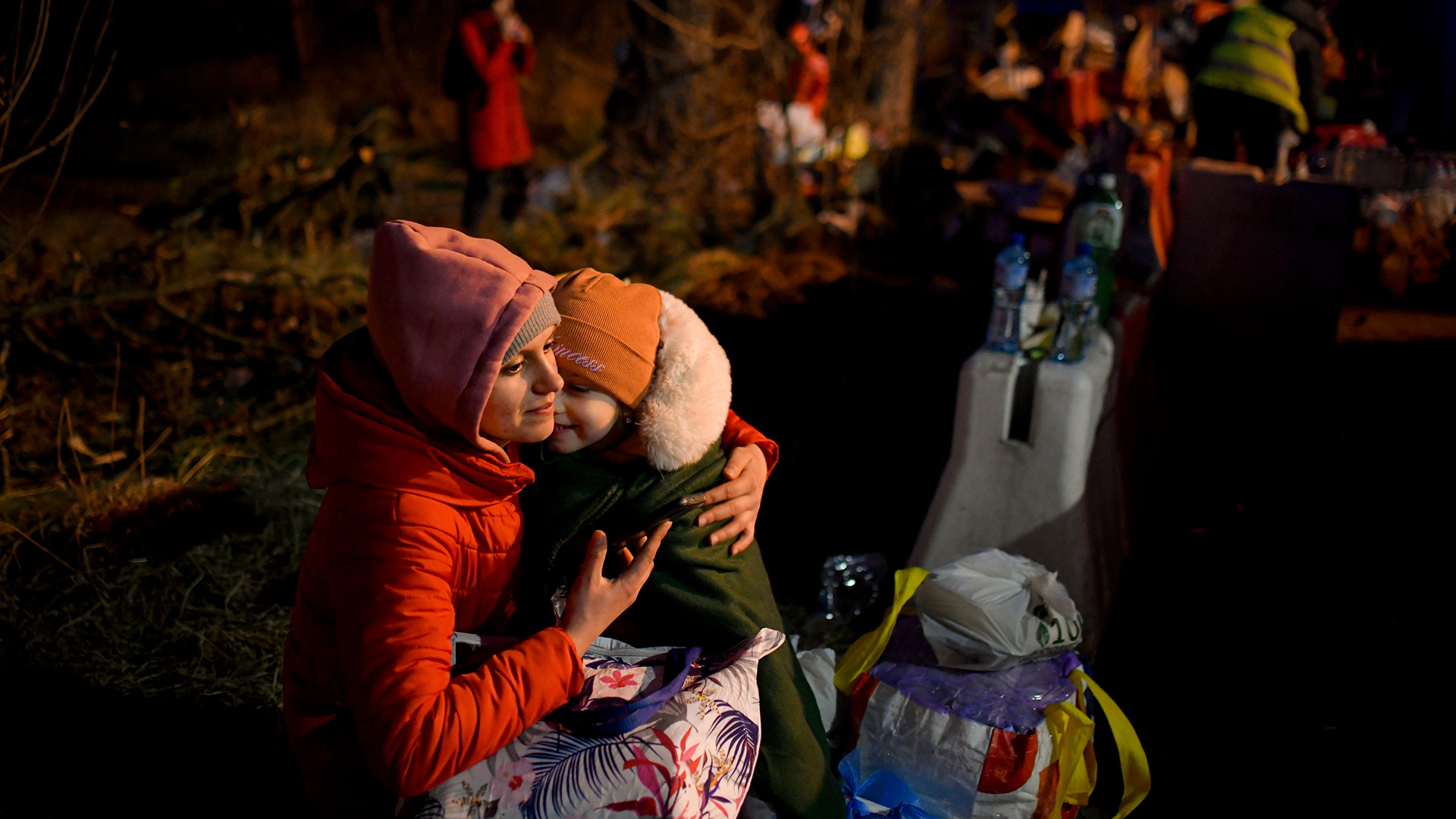 EIn Frau mit einem Kind auf dem Schoß sitzt an der rumänisch-ukrainischen Grenze in SIret, Rumänien. | AP