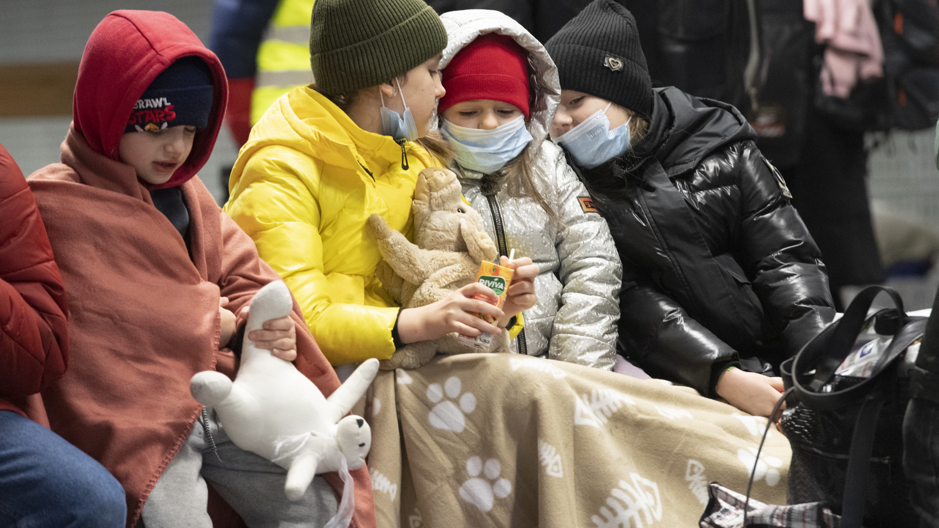 In Decken gehüllt sitzen Kinder aus dem ukrainischen Kriegsgebiet auf einer Bank im Berliner Hauptbahnhof. | dpa