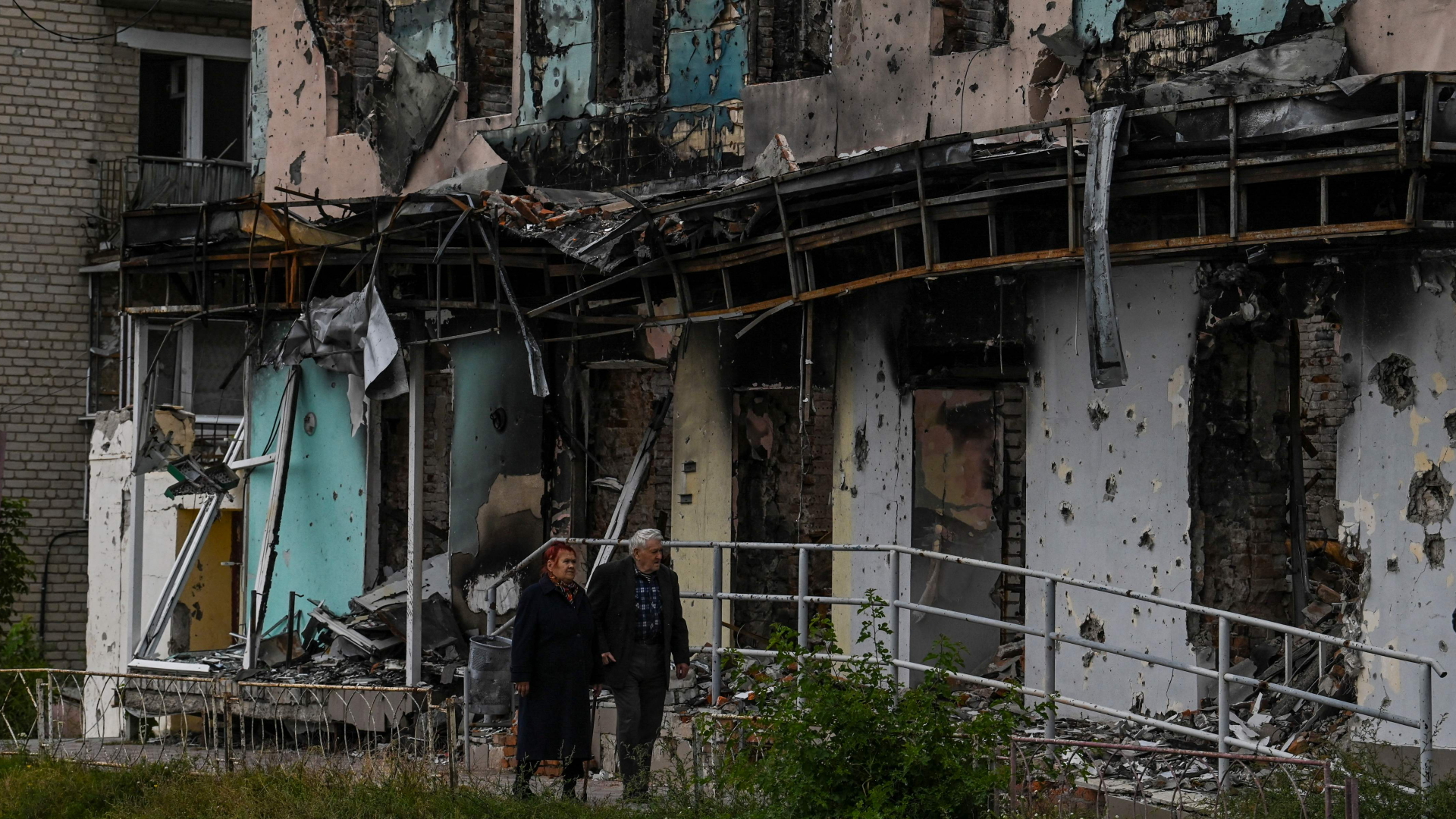 Ein älteres Paar läuft in der ukrainischen Stadt Isjum an durch Beschuss völlig zerstörten Häusern vorbei.