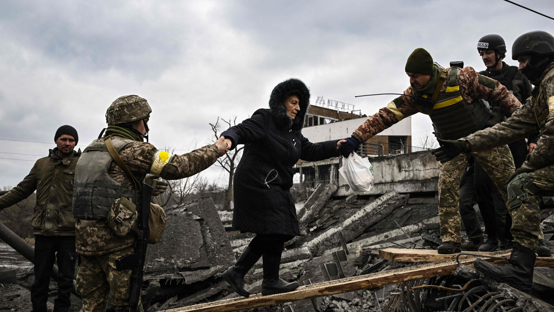 Im umkämpften Irpin in der Ukraine helfen Soldaten einer älteren Frau über Trümmer zu gelangen, um aus der Stadt zu entkommen. | AFP