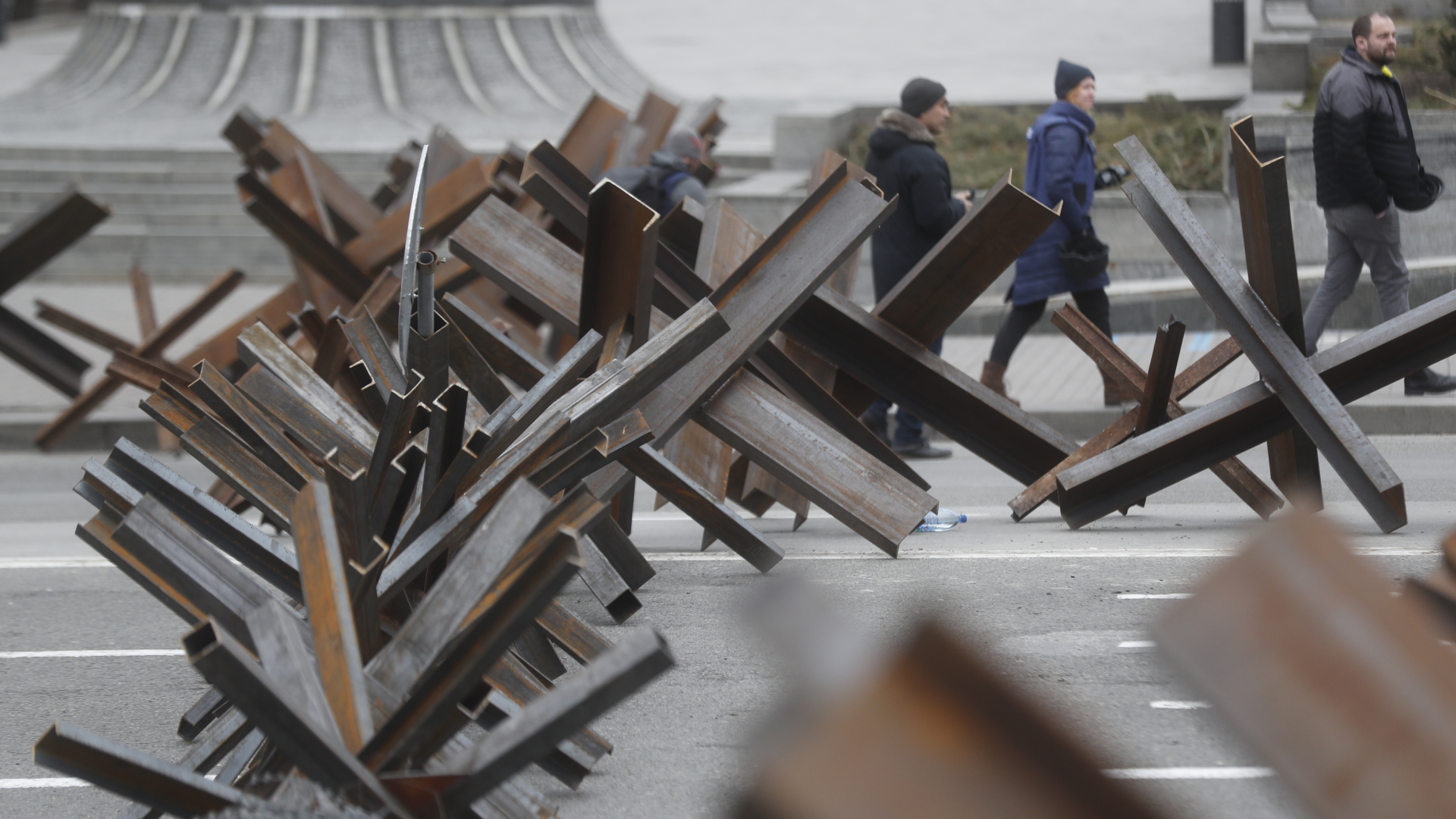 Menschen laufen an stählernen Barrieren in Kiew vorbei. | EPA