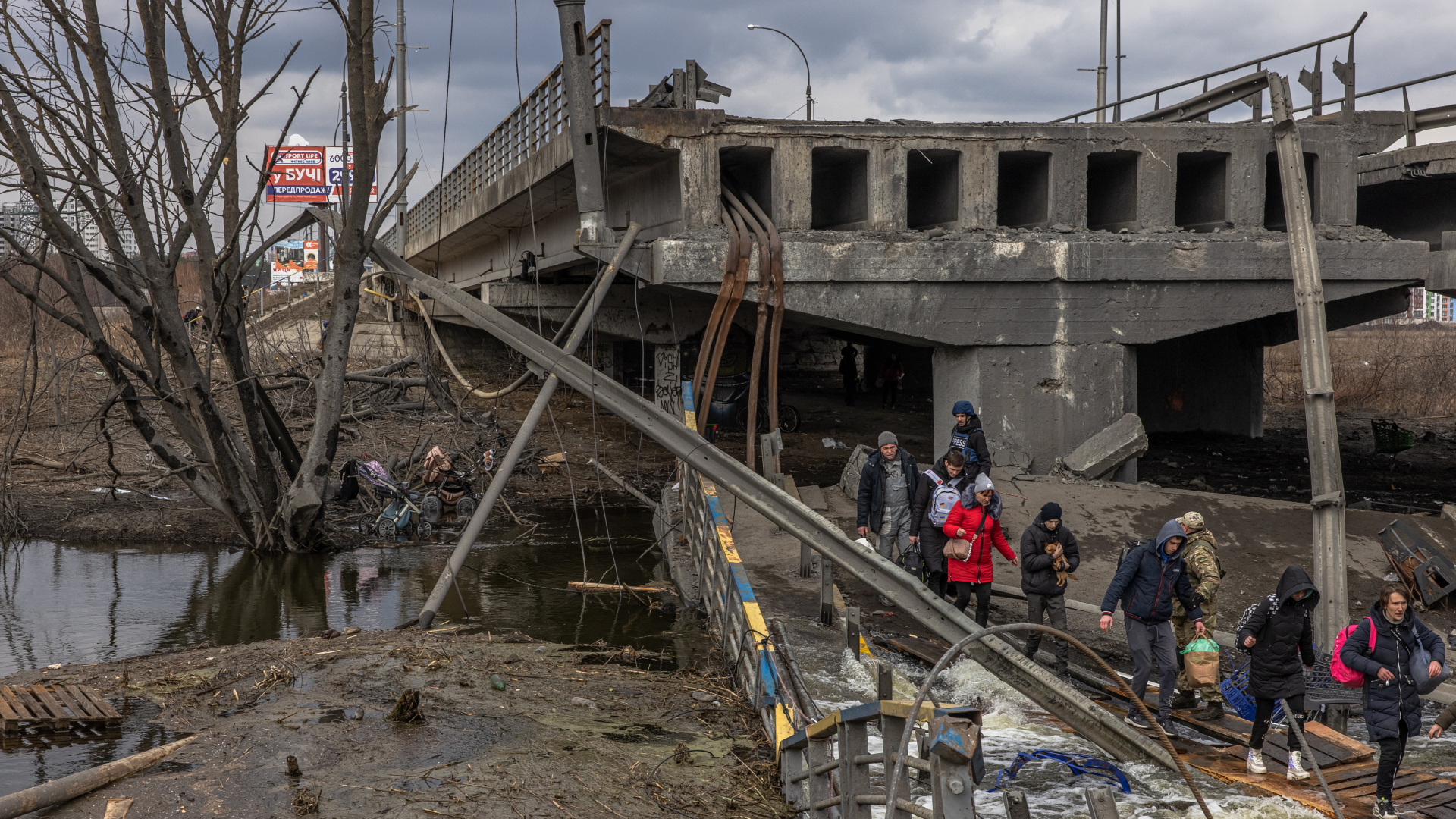 Menschen laufen an einer zerstörten Brücke in Kiew vorbei. | EPA
