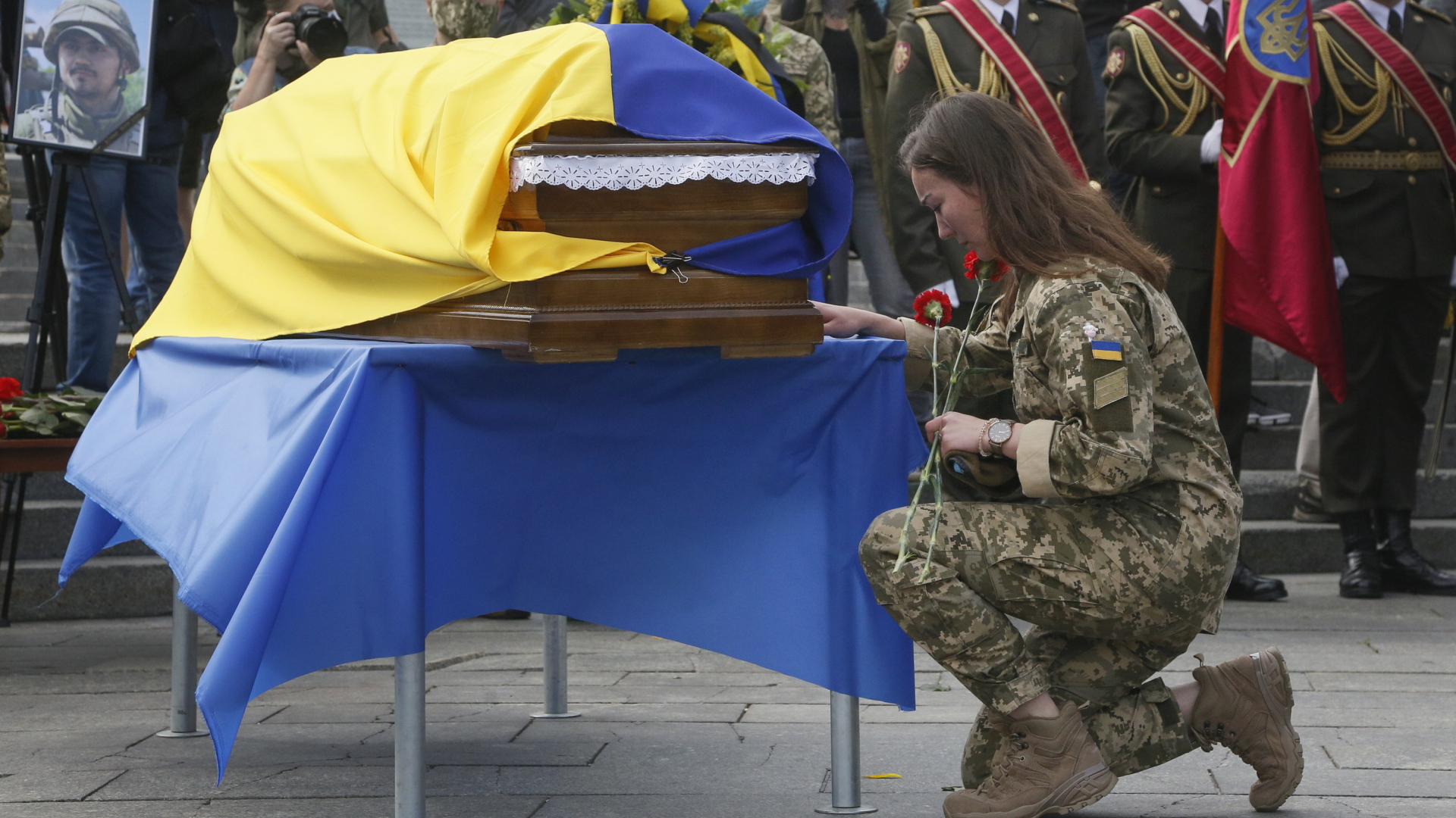 Eine ukrainische Soldatin kniet vor dem Sarg eines gefallenen Kameraden. | AP