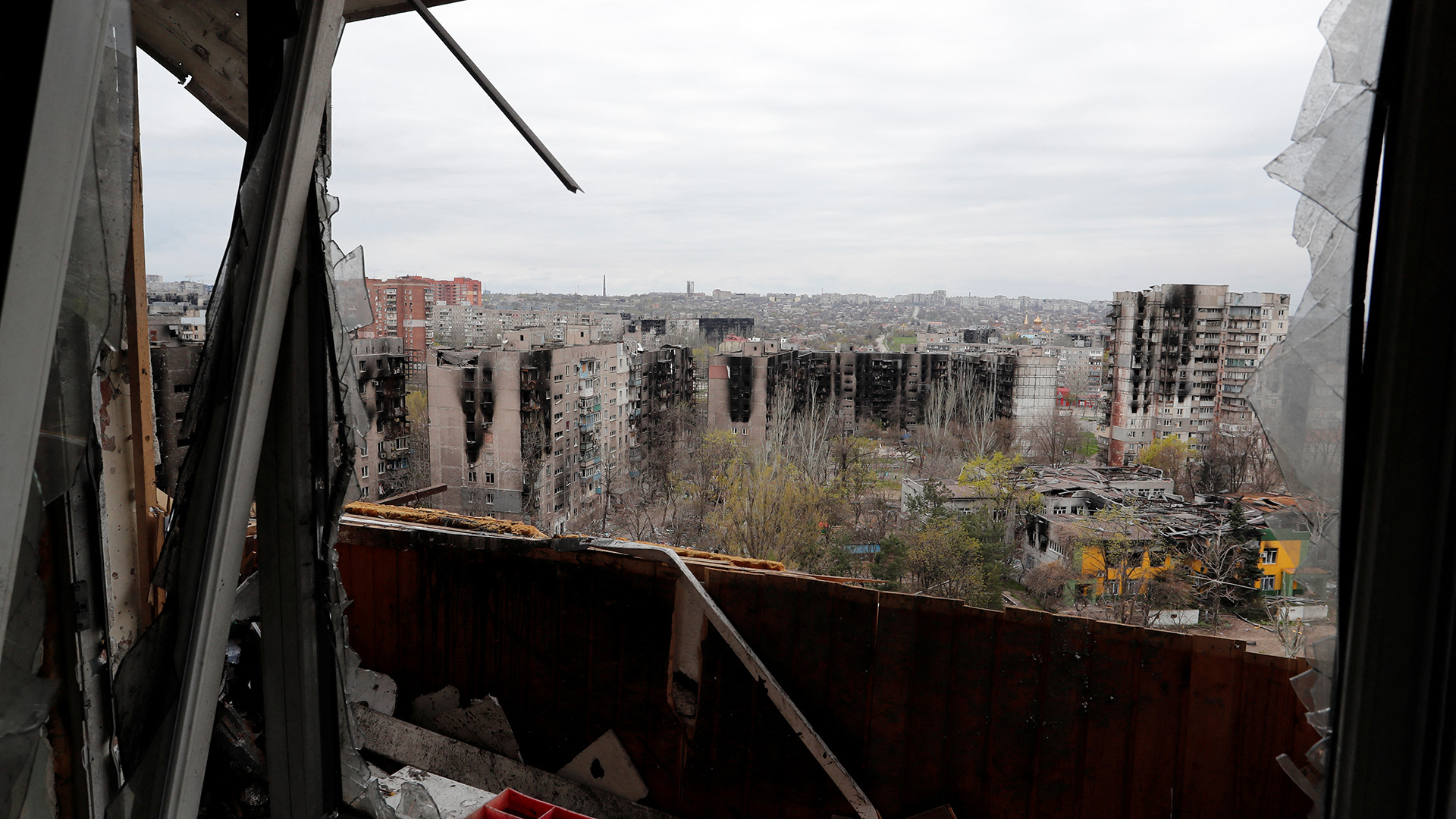 Aus einem Fenster sieht man die zerstörten Häuser in der Stadt Mariupol. | REUTERS