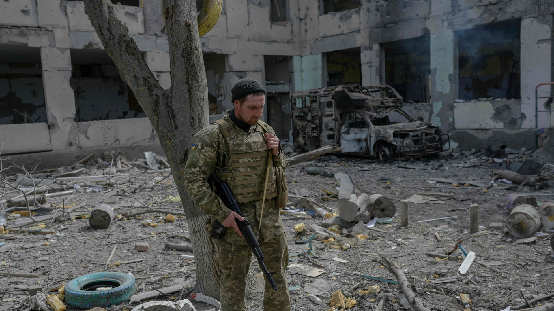 Ein ukrainischer Soldat vor einem zerstörten Schulgebäude. | AFP