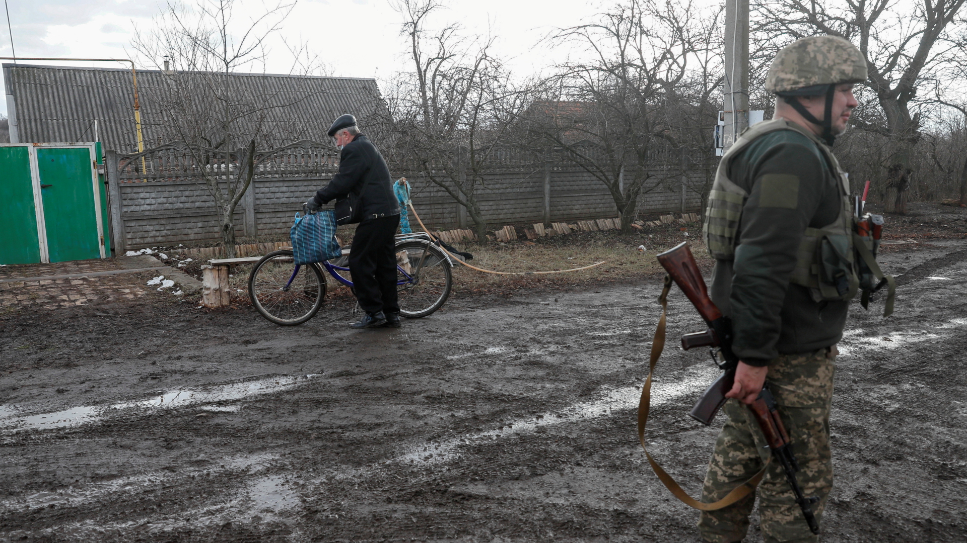 Im Dorf Novhorodske in der Region Donezk (Ukraine) schiebt ein Mann sein Fahrrad an einem bewaffneten Soldaten vorbei | REUTERS